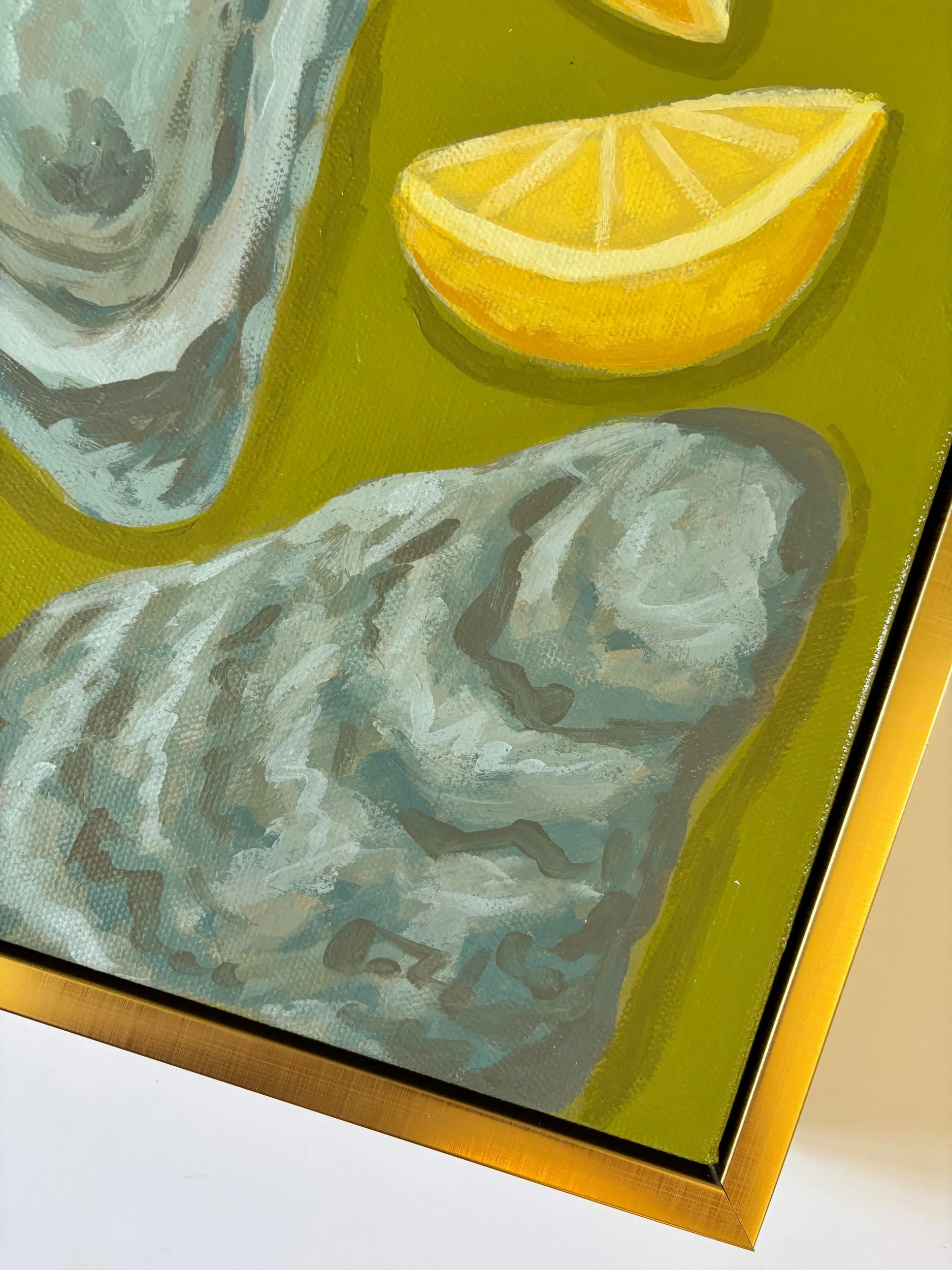 Oyster shell and lemon wedge painting on a rich green background in a gold frame, featuring coastal-inspired acrylic artwork with elegant Southern entertaining style.