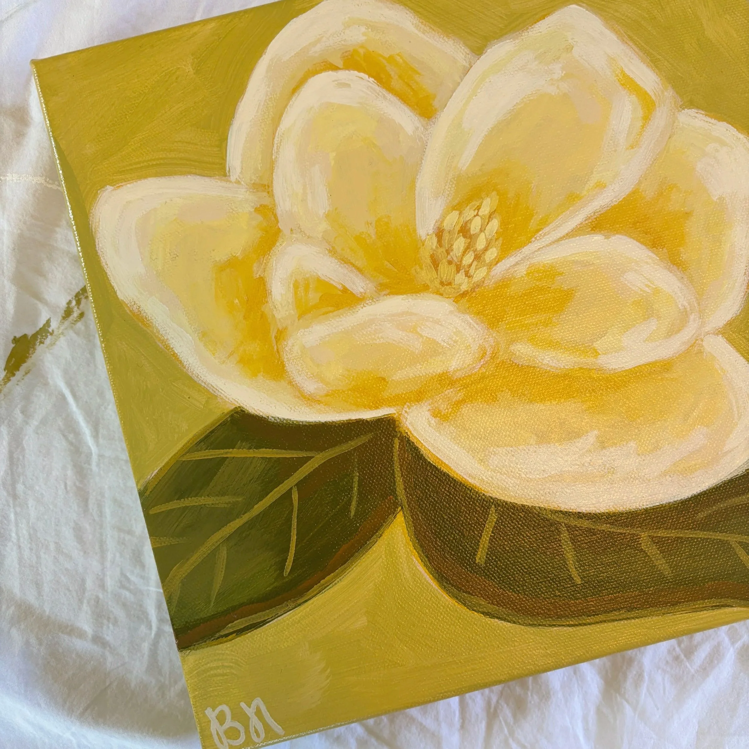 Original acrylic magnolia painting with a warm cream-colored bloom and soft green leaves set against a fresh lime green background.