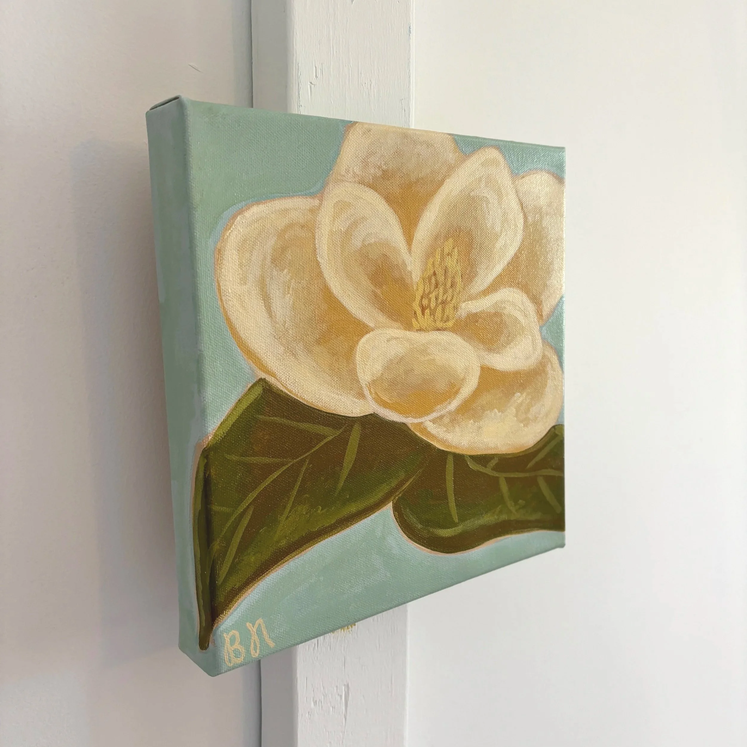 Original acrylic magnolia painting with cream blooms and soft green leaves on a light blue background.