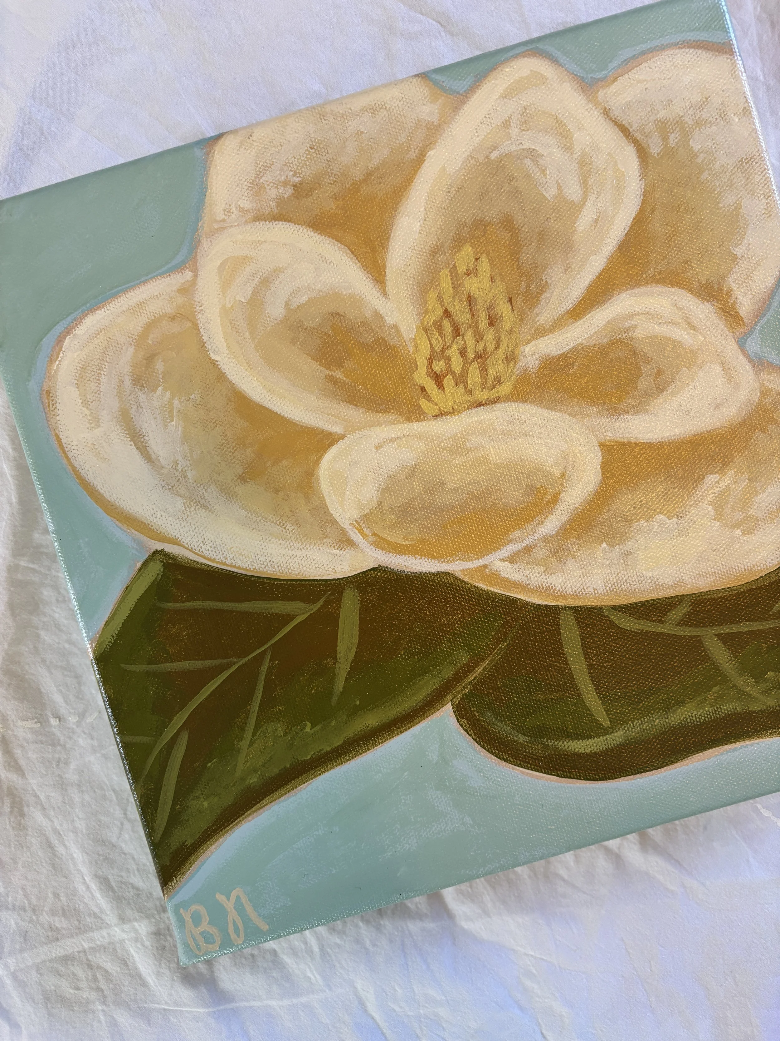 Original acrylic magnolia painting with cream blooms and soft green leaves on a light blue background.