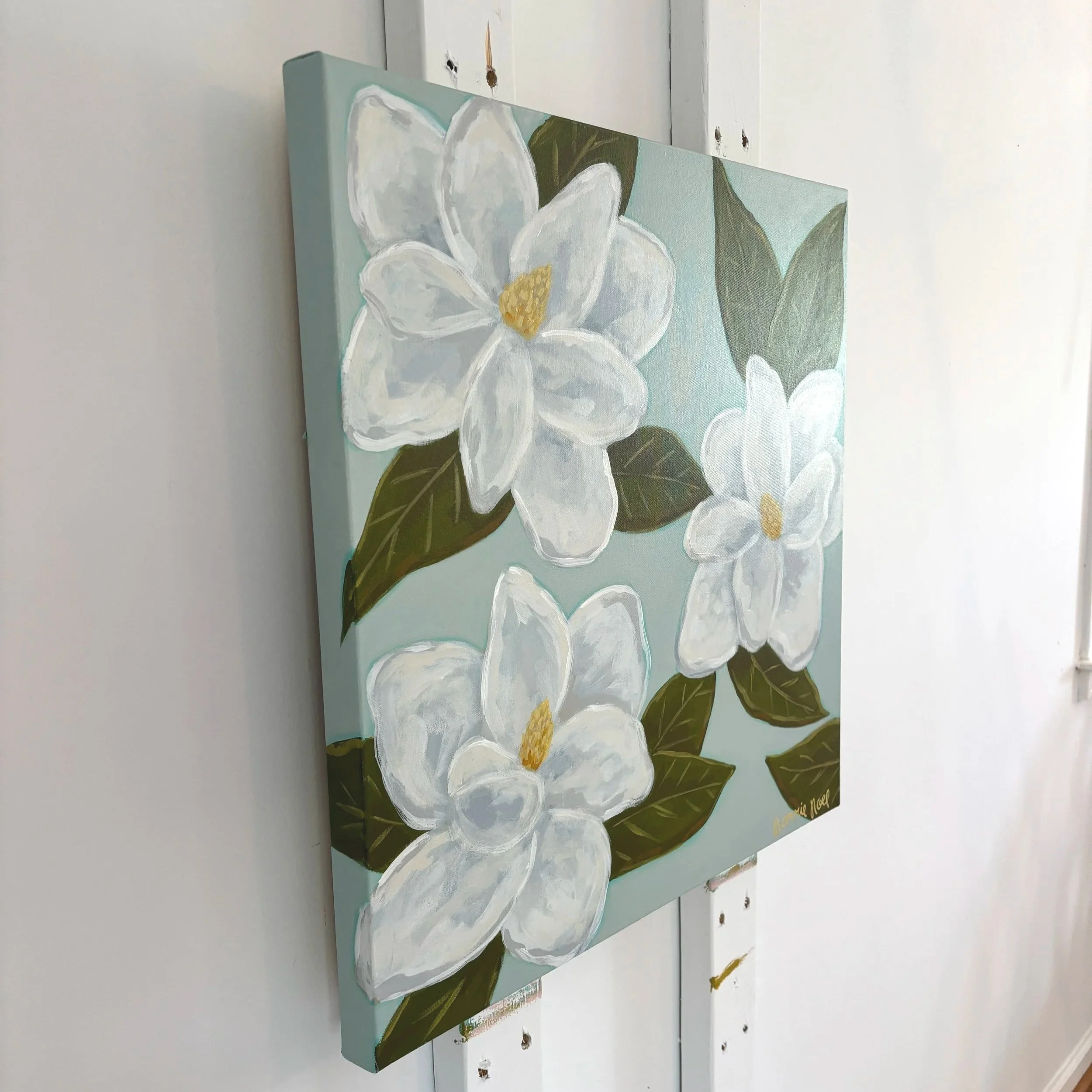 Original acrylic magnolia painting with creamy white blooms and soft green leaves on a light blue background.
