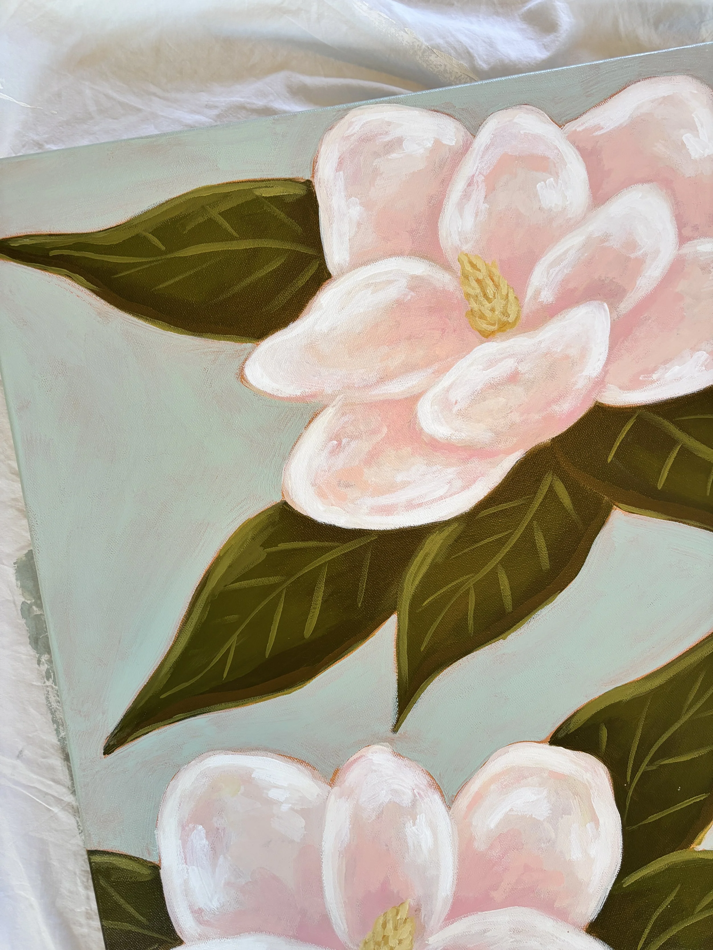 Original acrylic magnolia painting with pale pink blooms and soft green leaves on a light blue background.