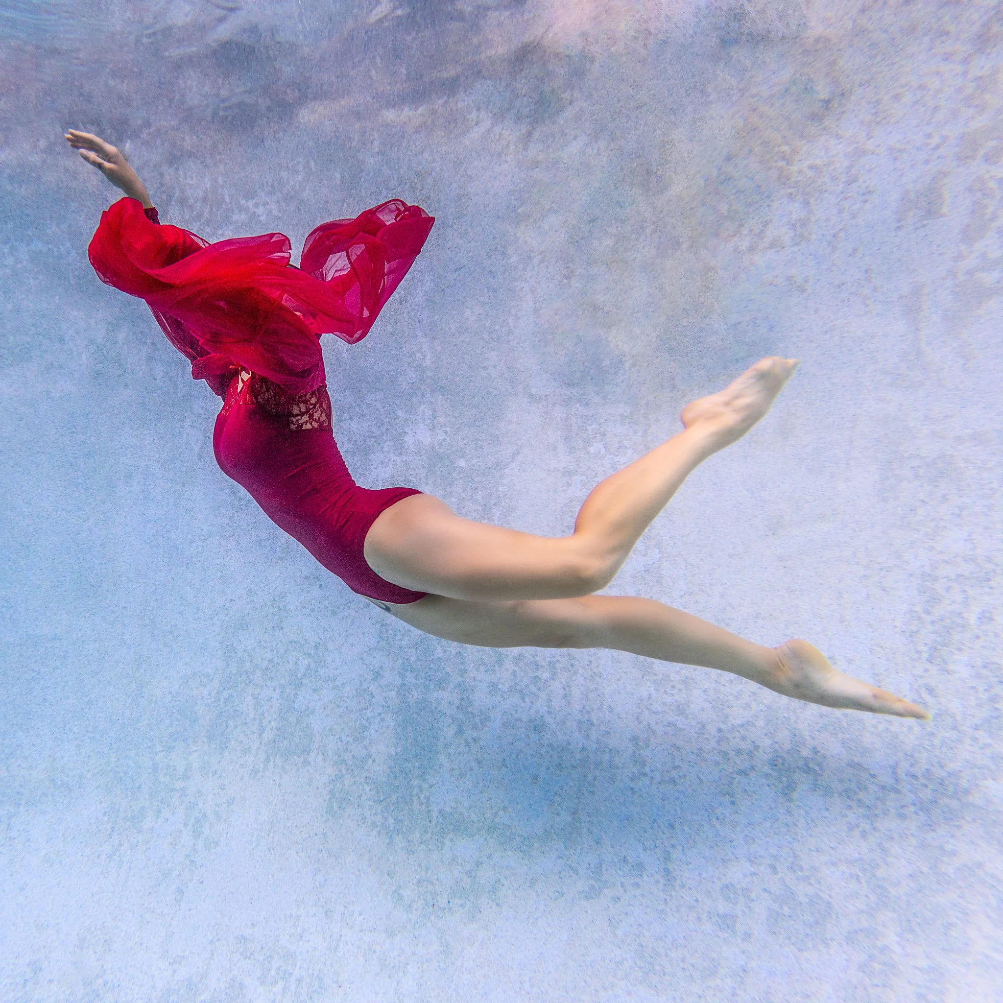 Lanie drifts in a bodysuit with red fabric in a heated 1960s swimming pool in Orlando, FL