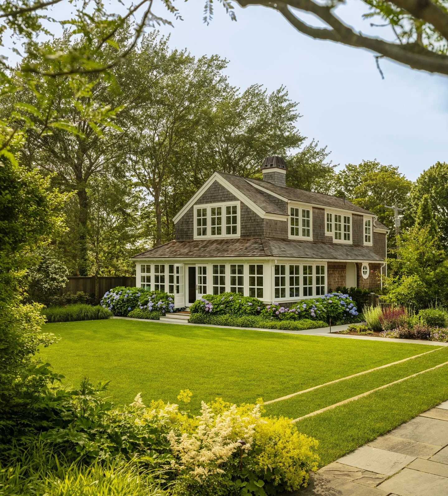 Hydrangeas frame this Cape Cod landscape, with lush layers of perennials around the main lawn to welcome guests and entertain all summer long. ⁠
⁠
Landscape architect: @gregorylombardidesign⁠
Photography: @landinophoto