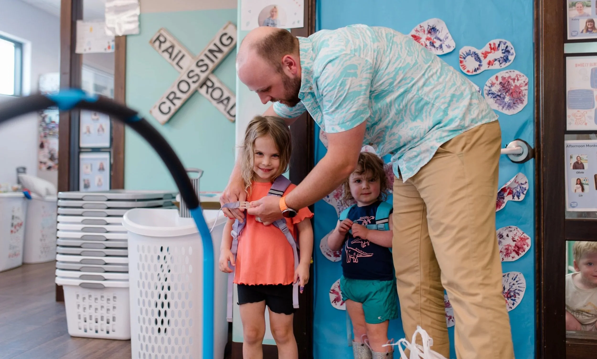 Dad putting backpack on young daughter