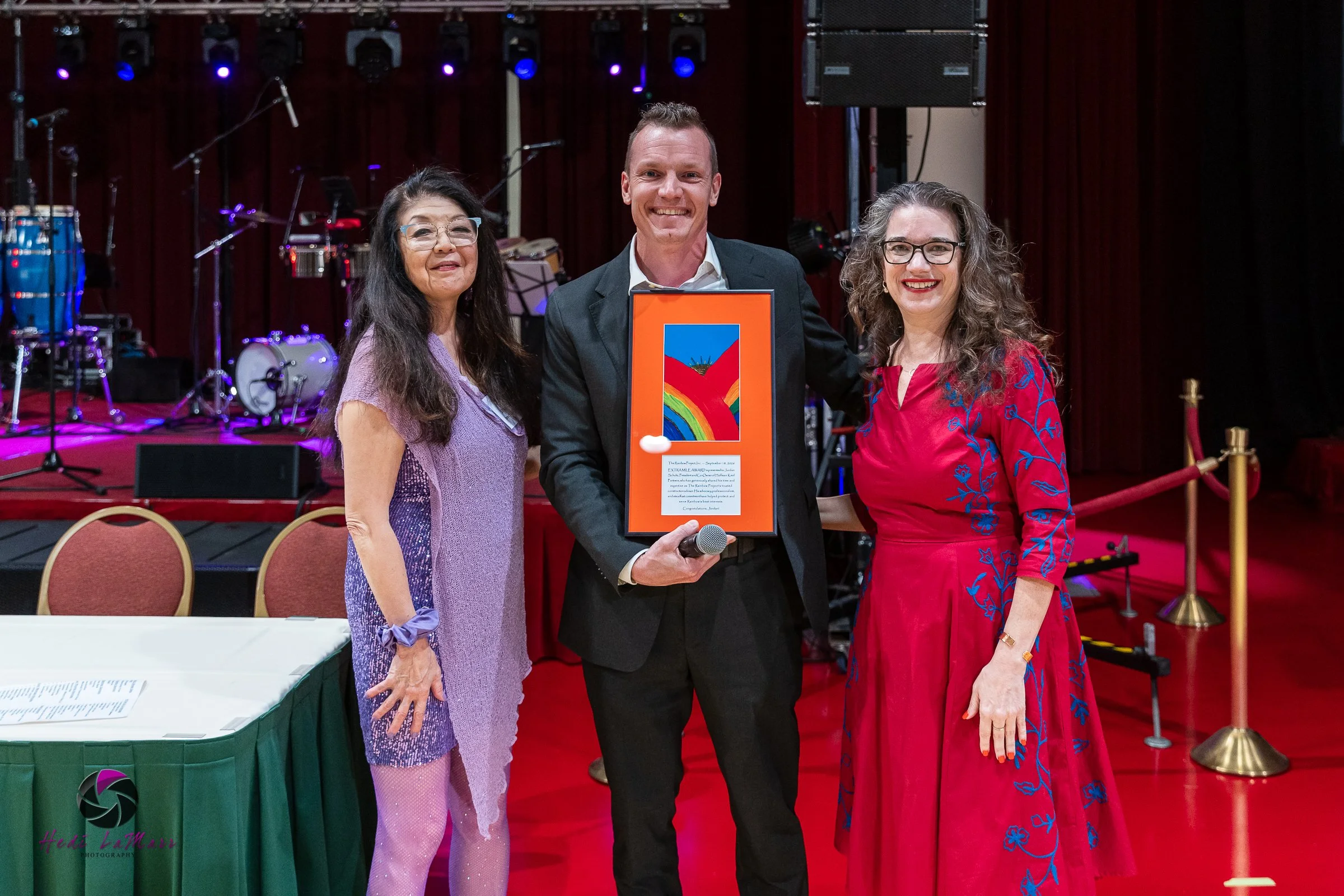 Jordan Schultz, 2026 Extra Mile Award Winner photographed with Sharyl Kato (left), Rainbow Project Founder and Executive Director and presenter Melisa Agard (right), Dane County Executive