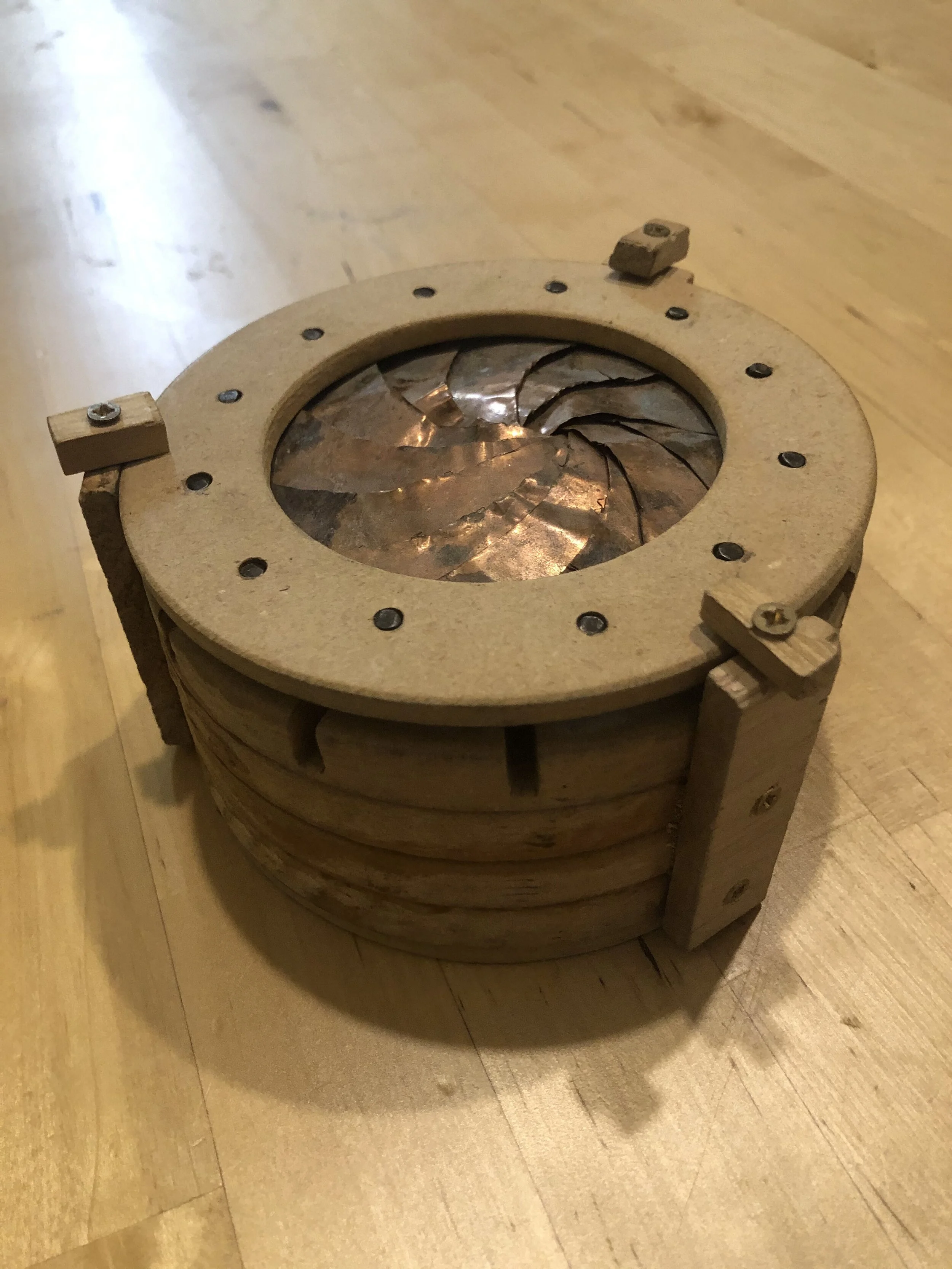 Mechanical Iris Box : One of my first woodworking projects using only a set of saws and a torch. Utilizes copper sheets brazed to steel pins to create an iris that opens and closes when rotated.   