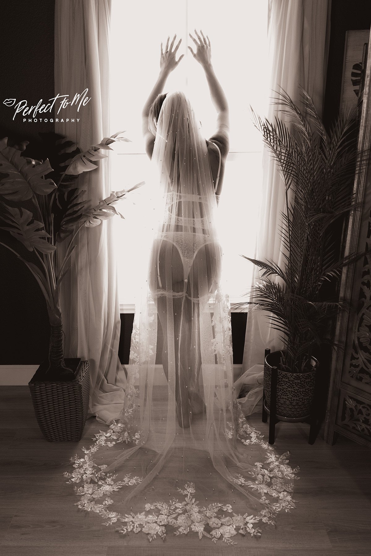 woman in white lingerie up against a window wearing long wedding veil boudoir photography