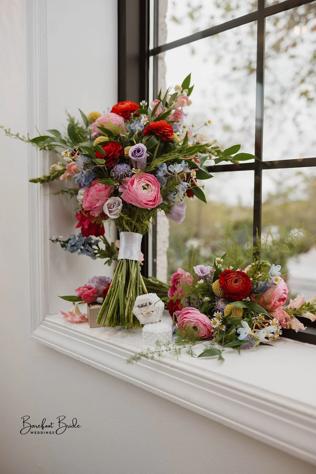 Colorful flower bouquet with pink, purple, and red flowers on windowsill, with additional flowers and rings in jewelry box.