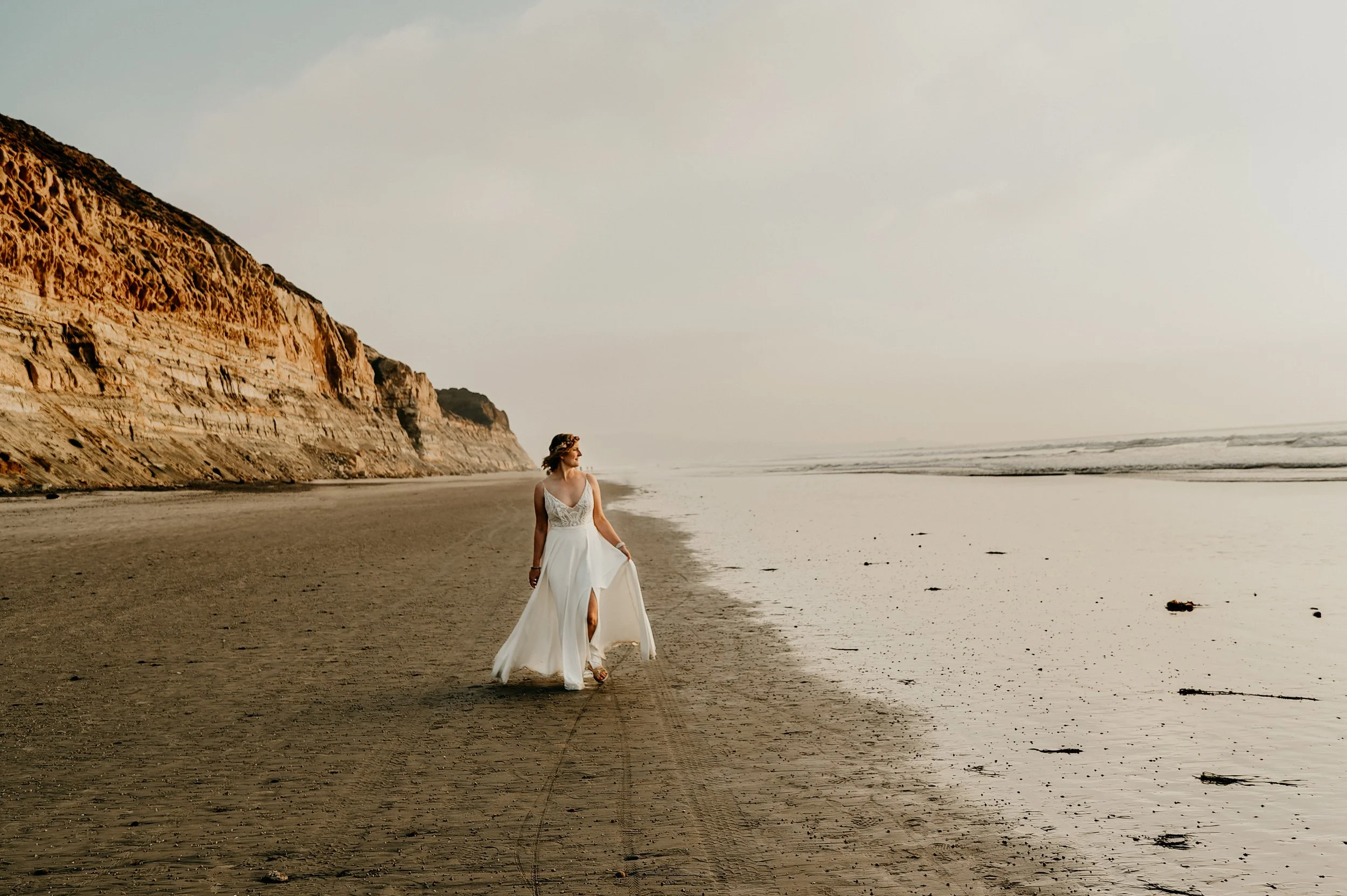 Torrey Pines elopement photographer San Diego — Bride walking on the beach below the Pacific Cliffs, Torrey Pines State Natural Reserve