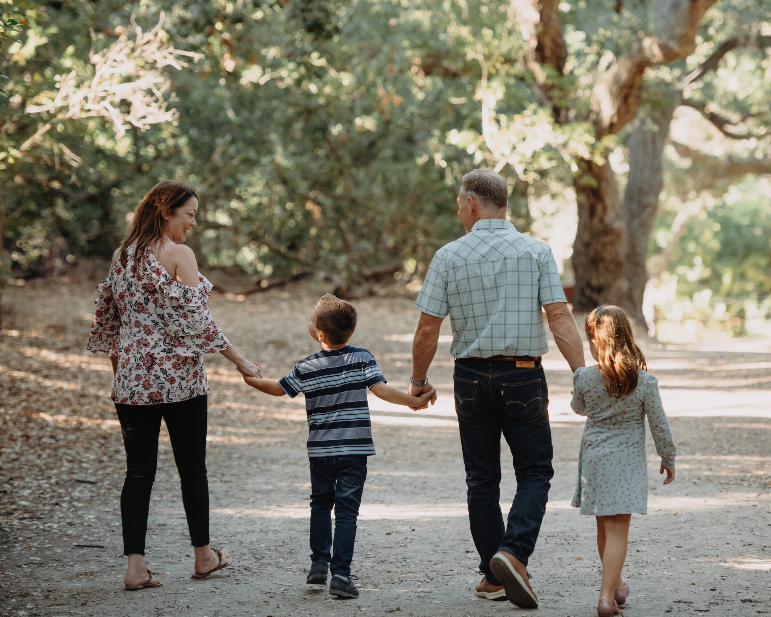 Family of four walking together in a straight line- in a wooded setting