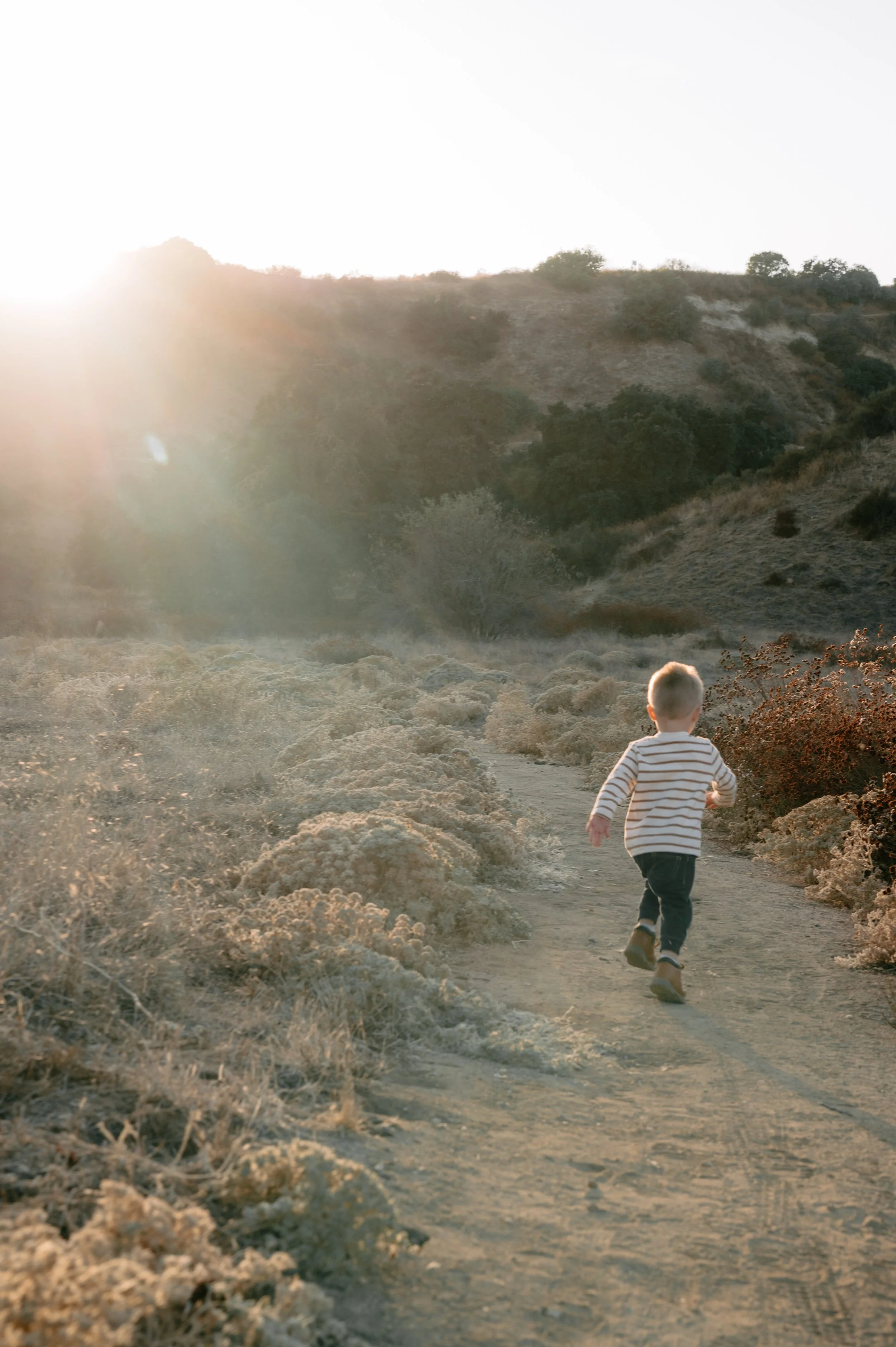 Toddler running ahead of everyone else, captured in the moment in motion during sunset