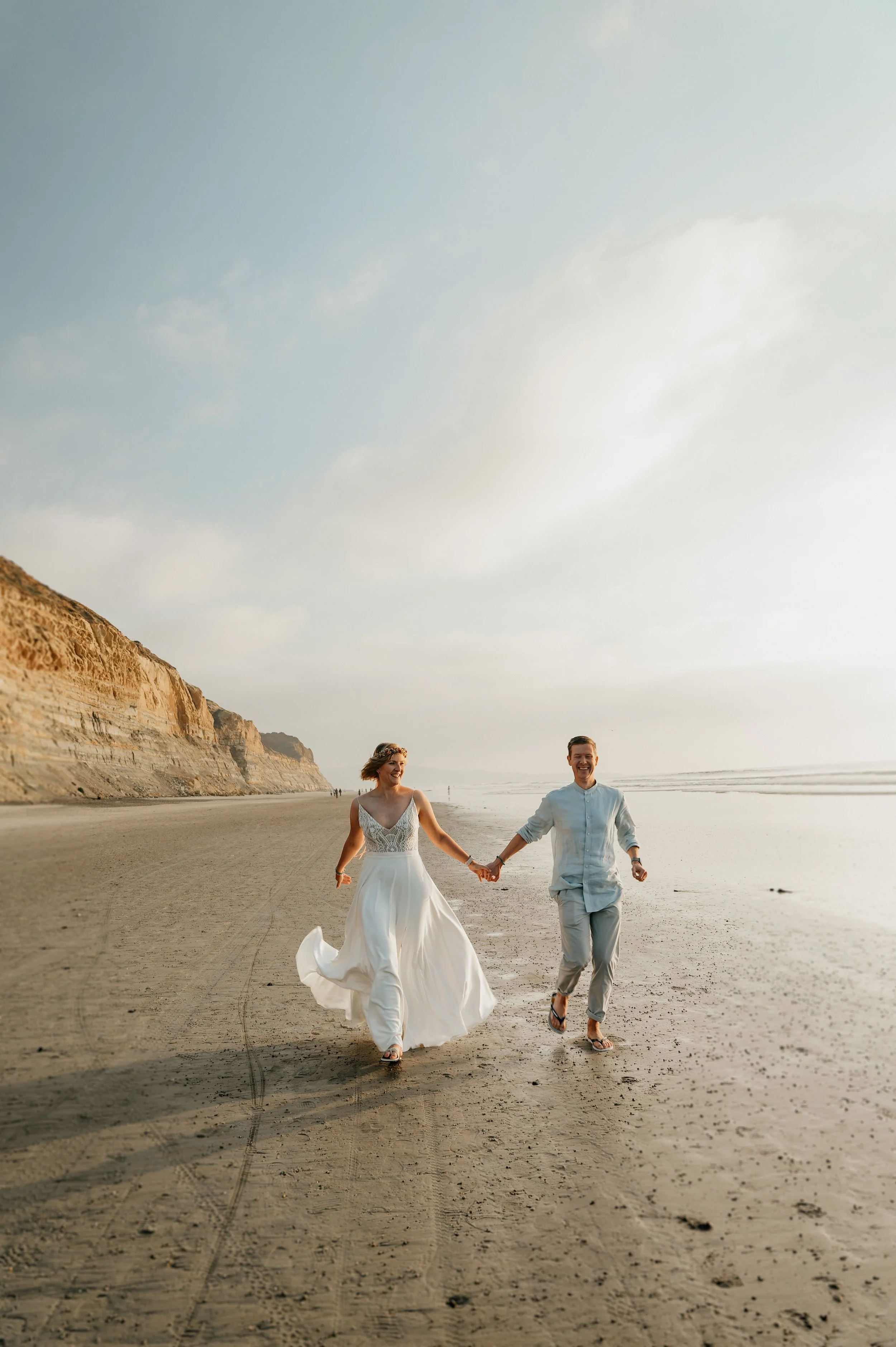 Torrey Pines elopement photographer San Diego — couple running on the beach below the Pacific Cliffs, Torrey Pines State Natural Reserve