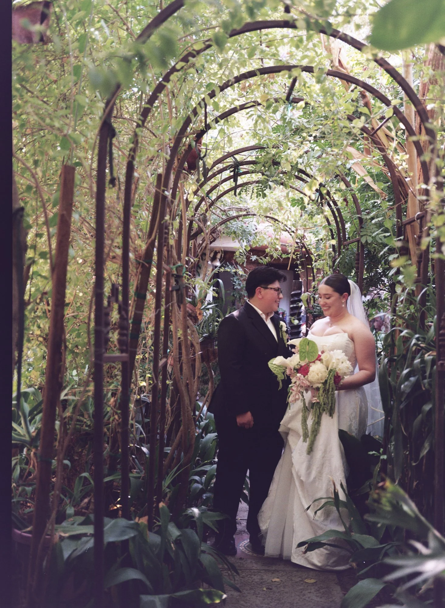 120mm film - gay couple elopement standing under a natural garden archway