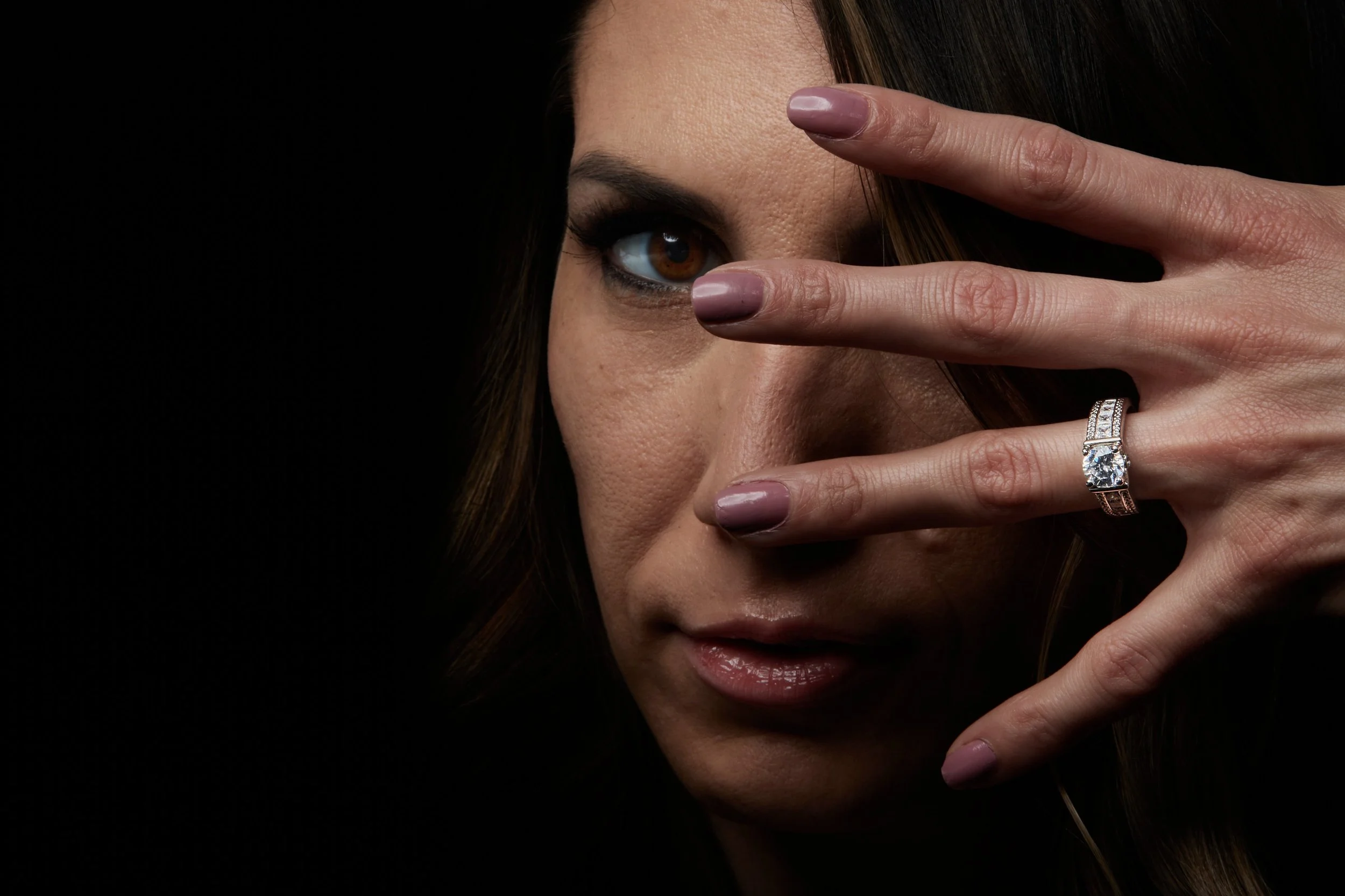the woman with a beautiful ring and a big CenterStone what shows the sparkles of the diamond jewelry while with her long hair looking thru the fingers by torsten glaenzel