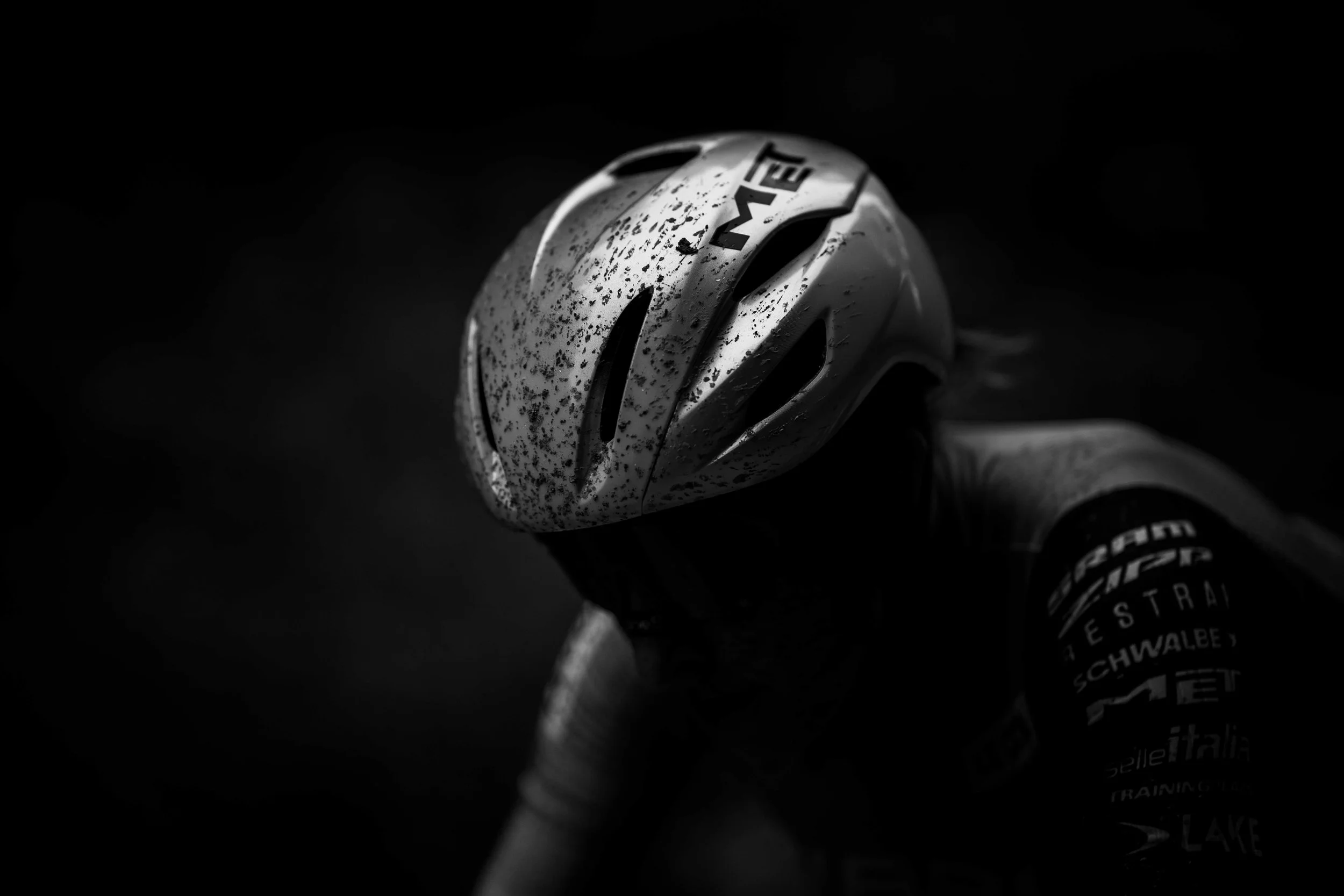 Shot of a speckled white cycling helmet on a bicycle handlebar in low light.