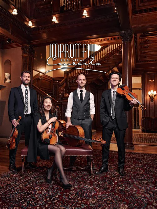 Classical music ensemble with three men and one woman, holding string instruments, in a grand wooden hall with ornate architecture and warm lighting.