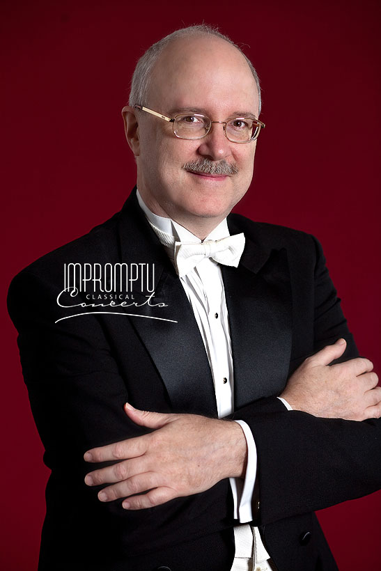 A man in formal tuxedo with a bow tie, glasses, and a mustache, standing against a red background with his arms crossed, promoting a classical concert.