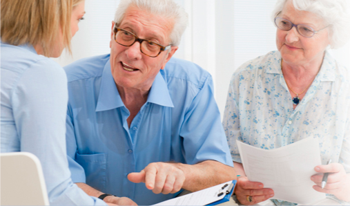 Senior man and woman talking with healthcare provider in a consultation room.