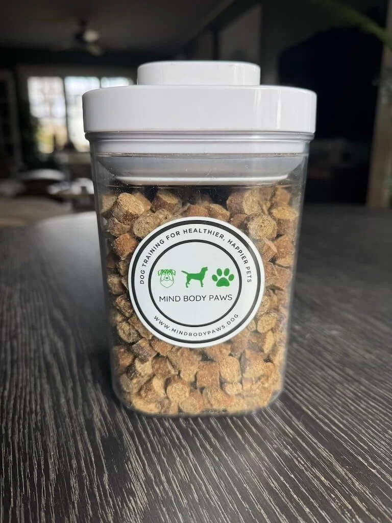 Dog training treat jar in a living room used for rewarding calm behavior at home.I keep this airtight OXO treat jar in my living room so I can reward my dogs for calm behavior while I’m working.