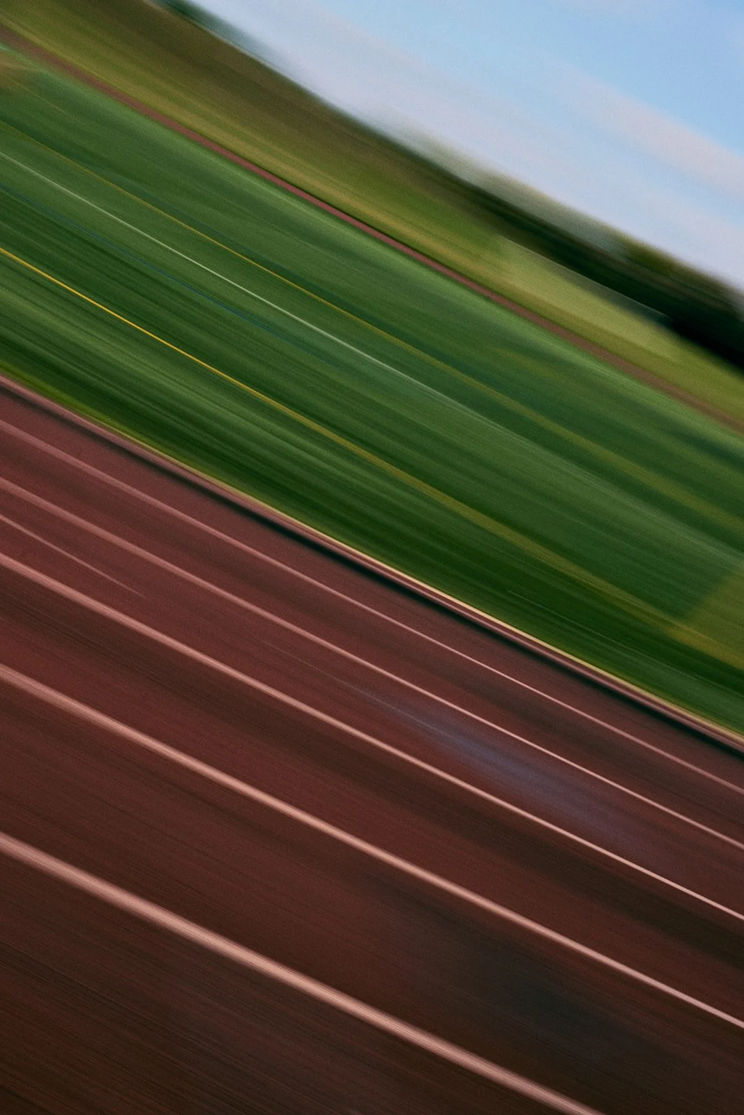 Blurry image of a colorful landscape with green, brown, and blue hues, suggesting a scenic view or aerial shot.