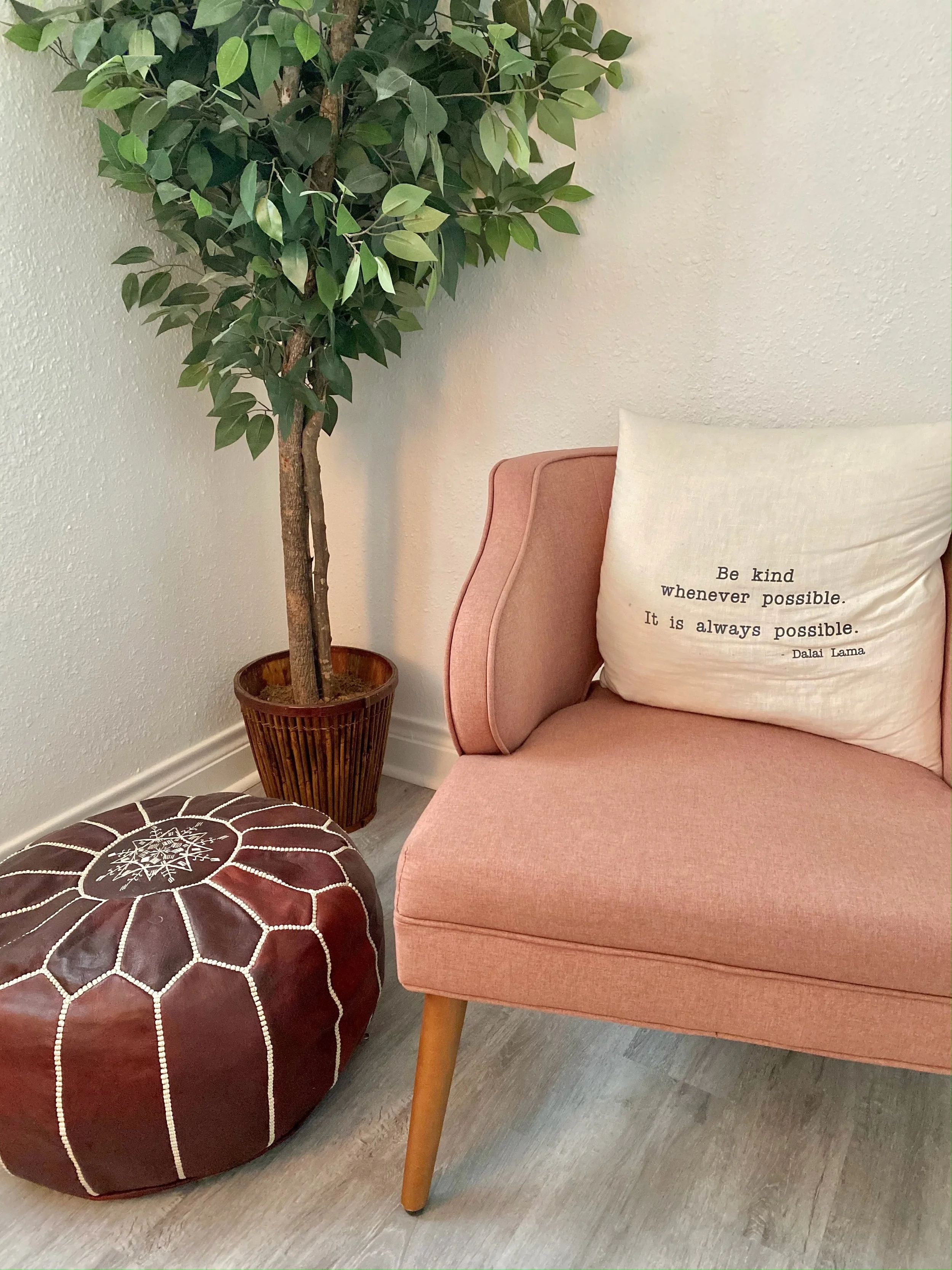 Pink therapy chair with brown floor pouf and tree