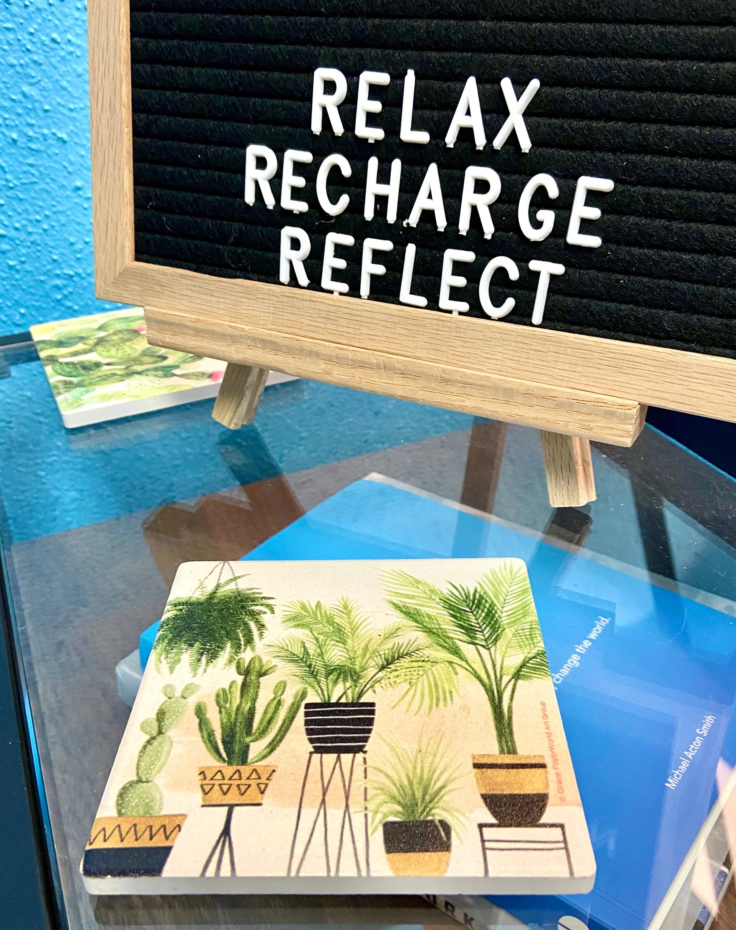 relax, recharge, reflect on board with botanical book on glass table