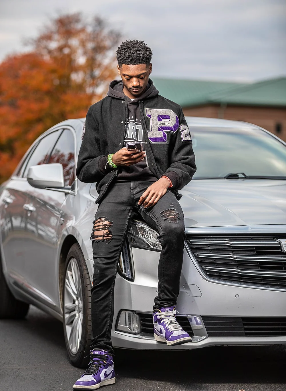 Senior with his car in a varsity jacket