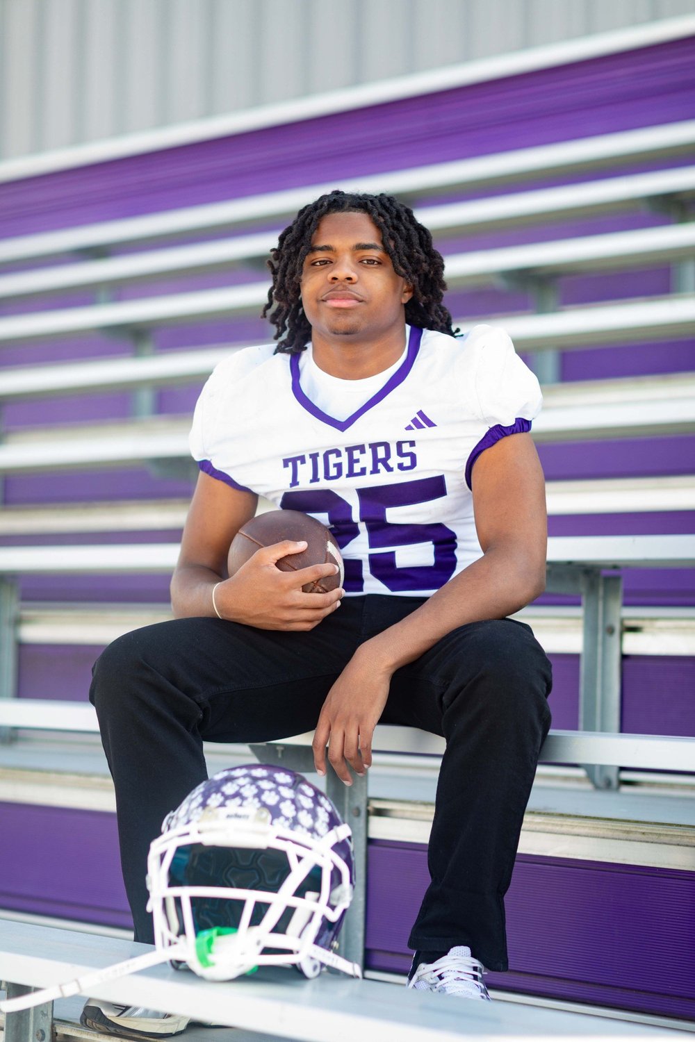 Football senior in white Tigers jersey on the bleachers