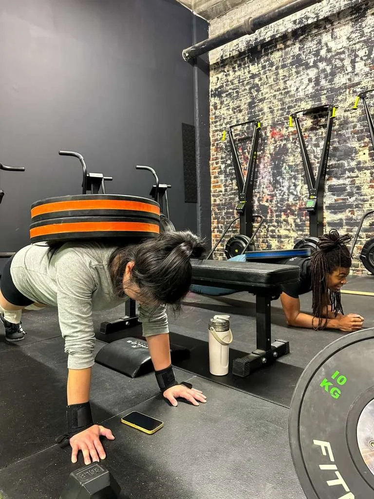 Person flipping a large tire in a gym with "Resilient Strength" on the wall.