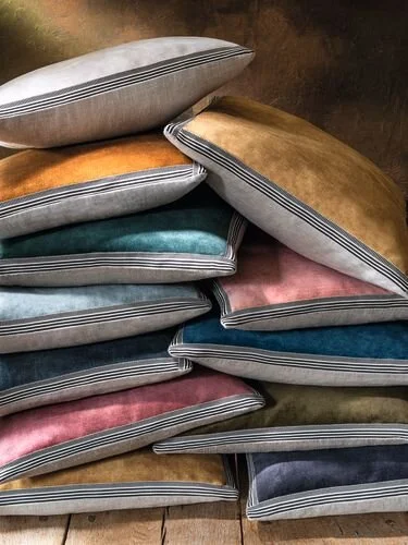 Two stacks of Maison Casamance Manade velvet cushions in gold, pale blue, teal, pink, navy and olive (shared photo, Manade Cushion – Nacre)