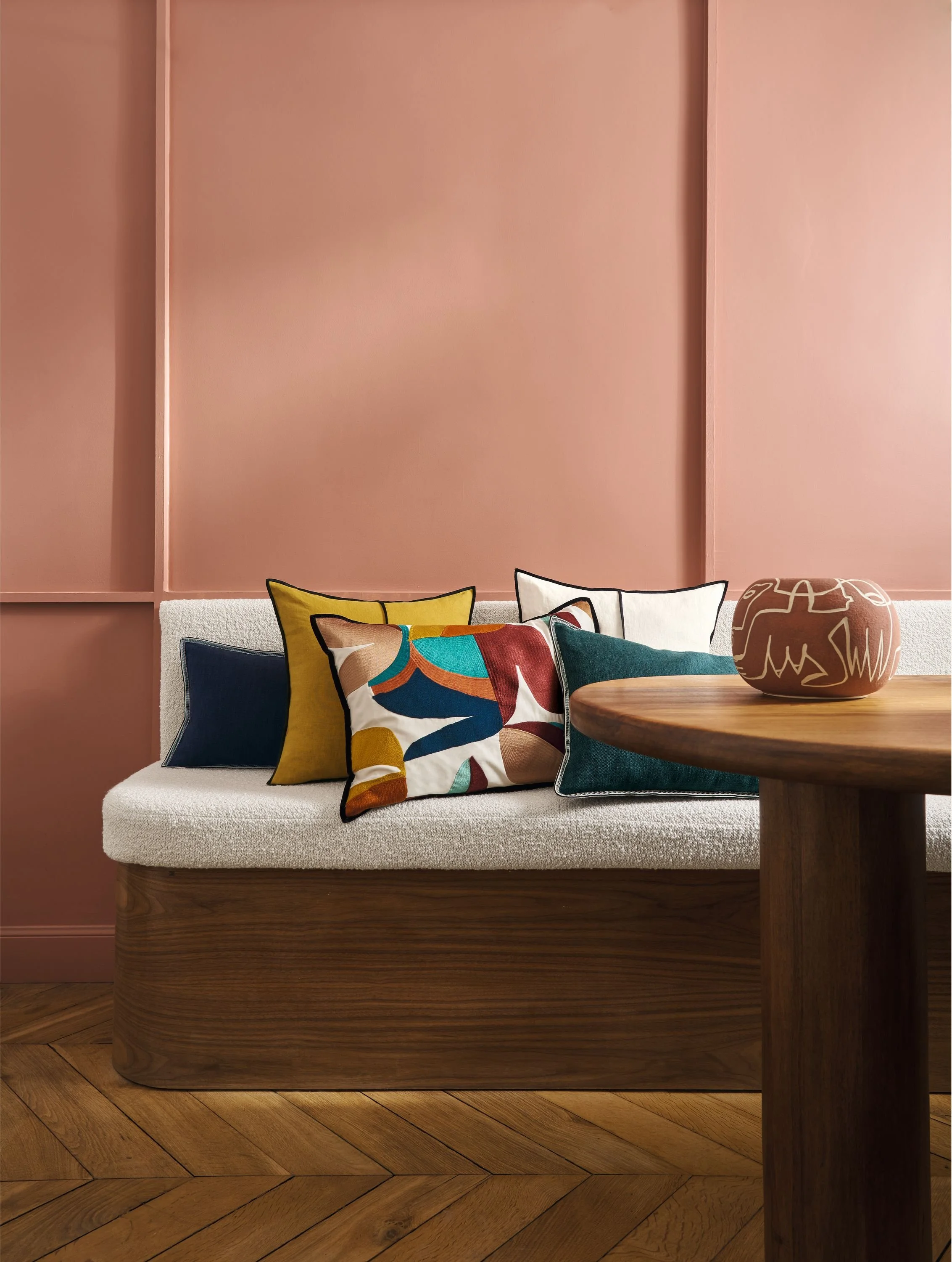 Maison Casamance cushions including Linen on a white bench against a blush pink wall