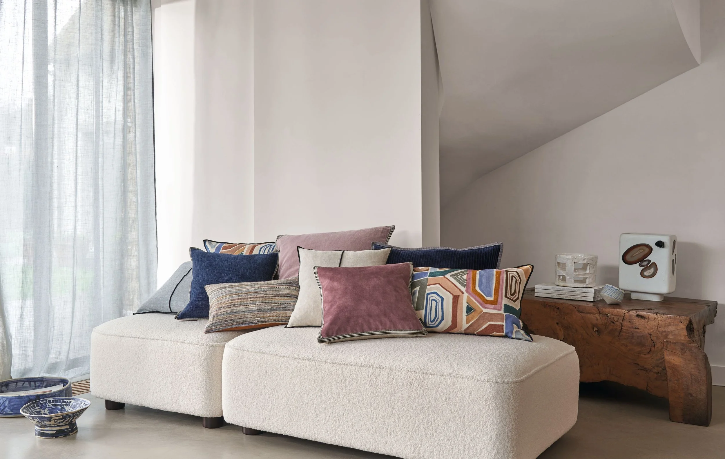 Cream bouclé sofa with Maison Casamance Manade cushions in navy and rose mixed with patterned cushions