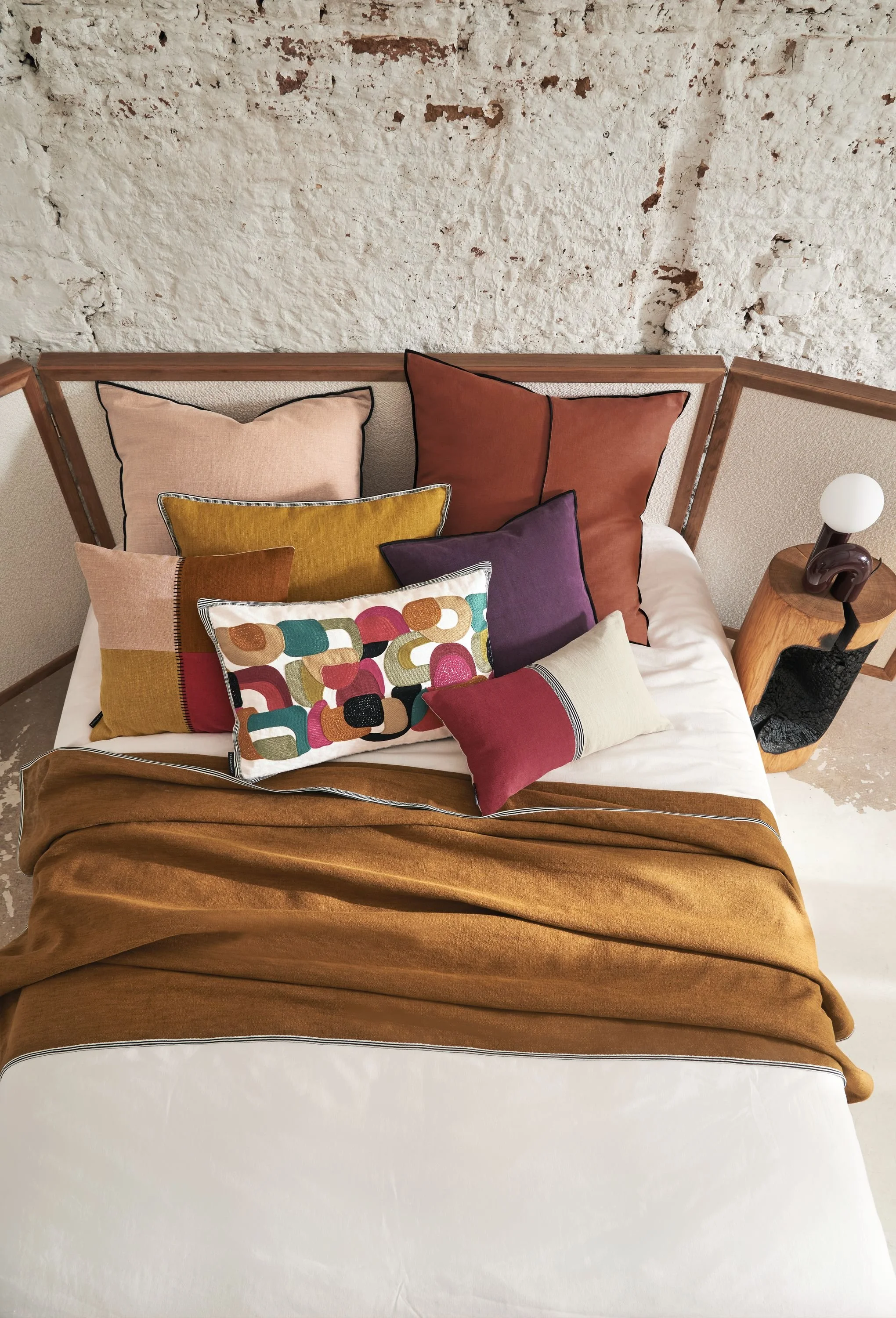 Maison Casamance Guéthary throw in Ocre on a bed with cushions