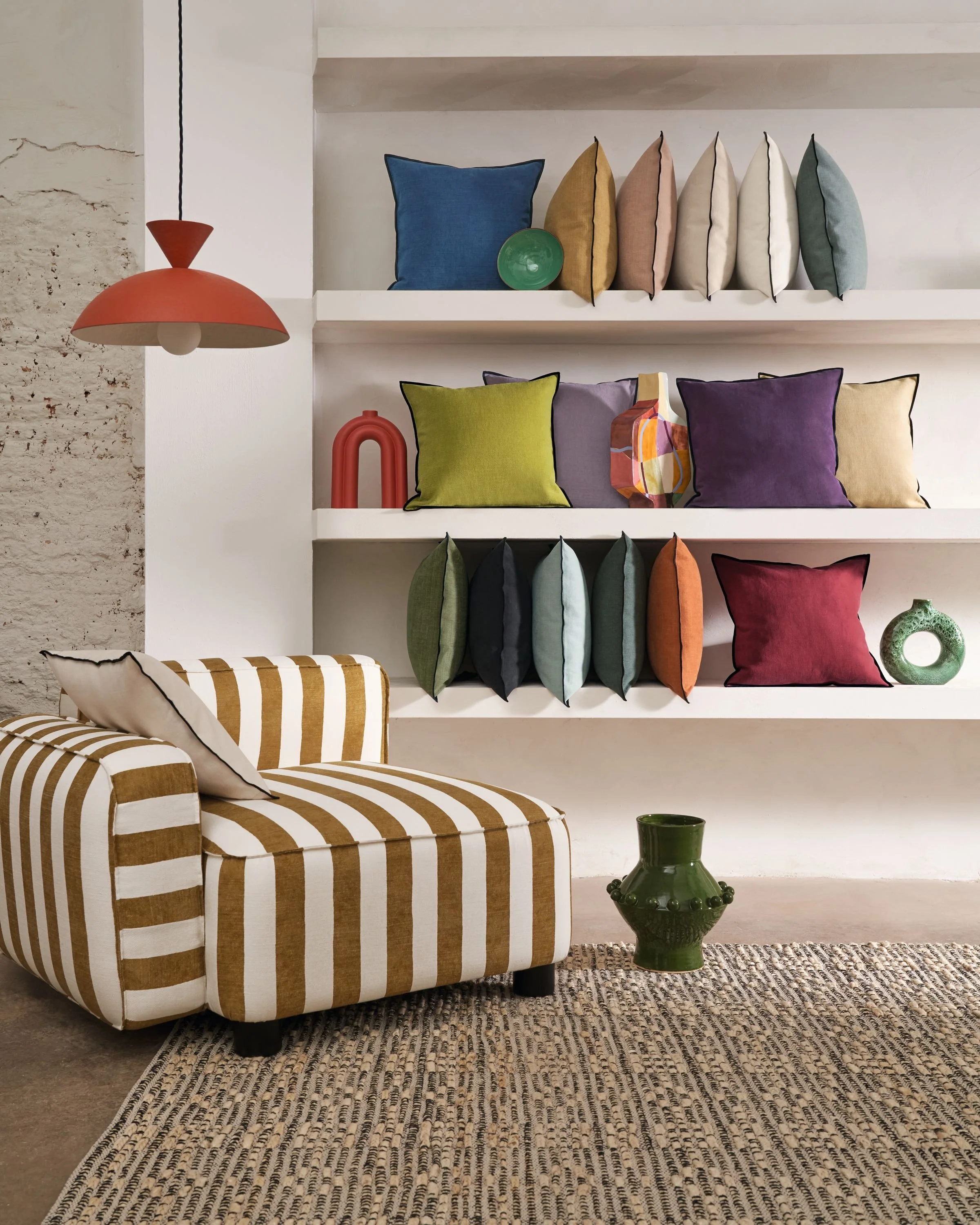 Maison Casamance Paris Texas cushions in mixed colours on shelves above a striped armchair