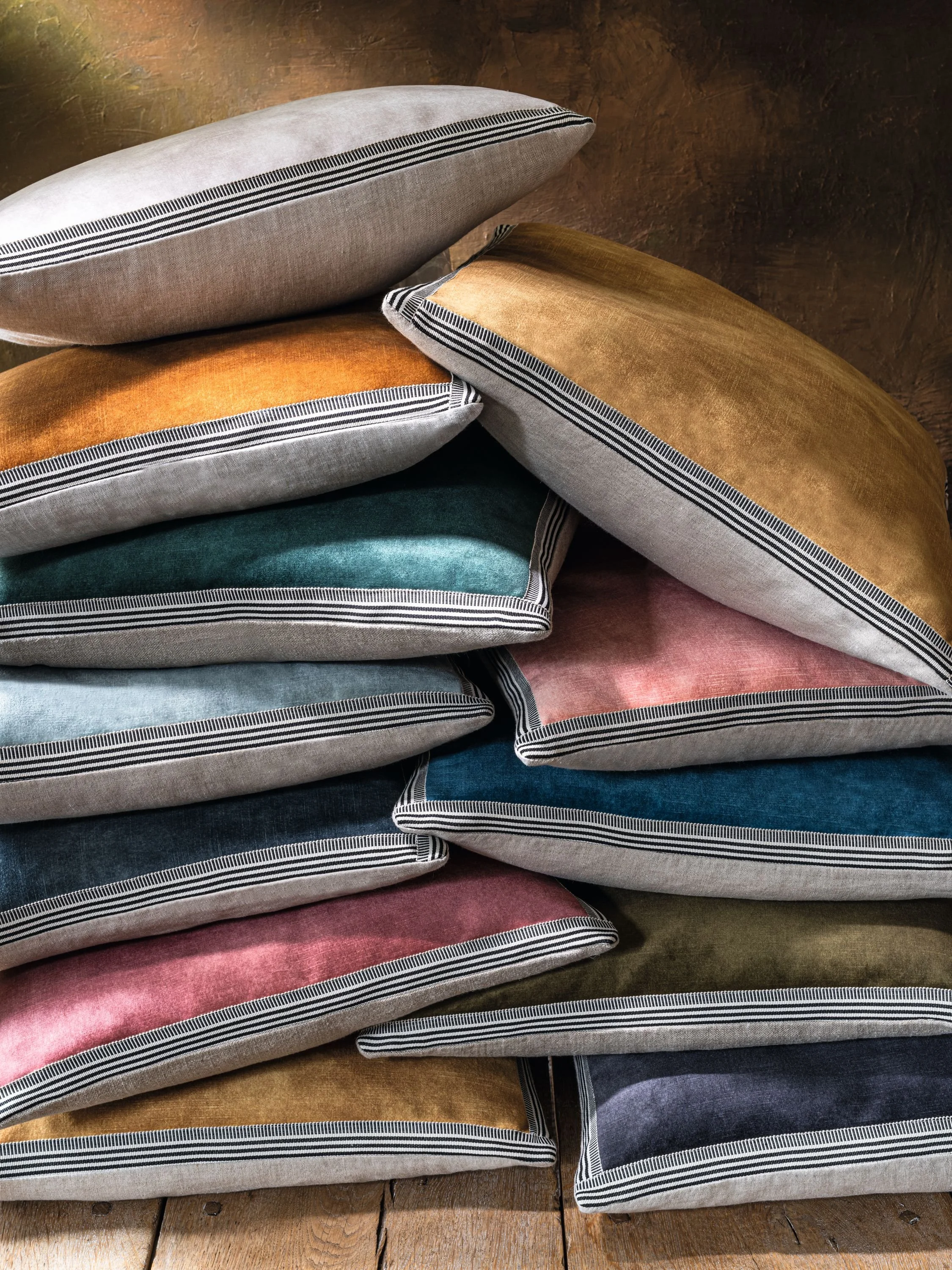 Stack of Maison Casamance Manade velvet cushions in blue, pink, ochre and grey