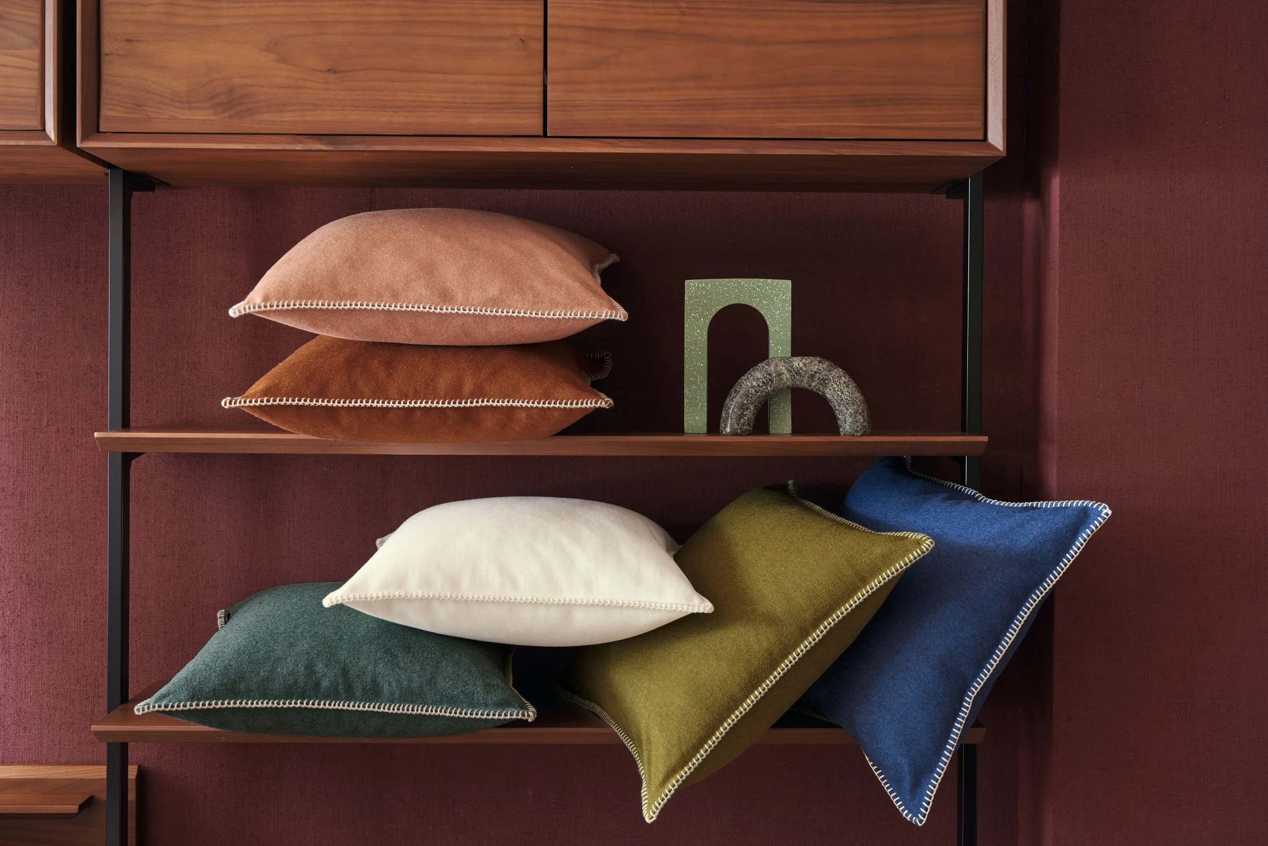 Maison Casamance Arthur's Seat wool cushions in mixed colours on a wooden shelf