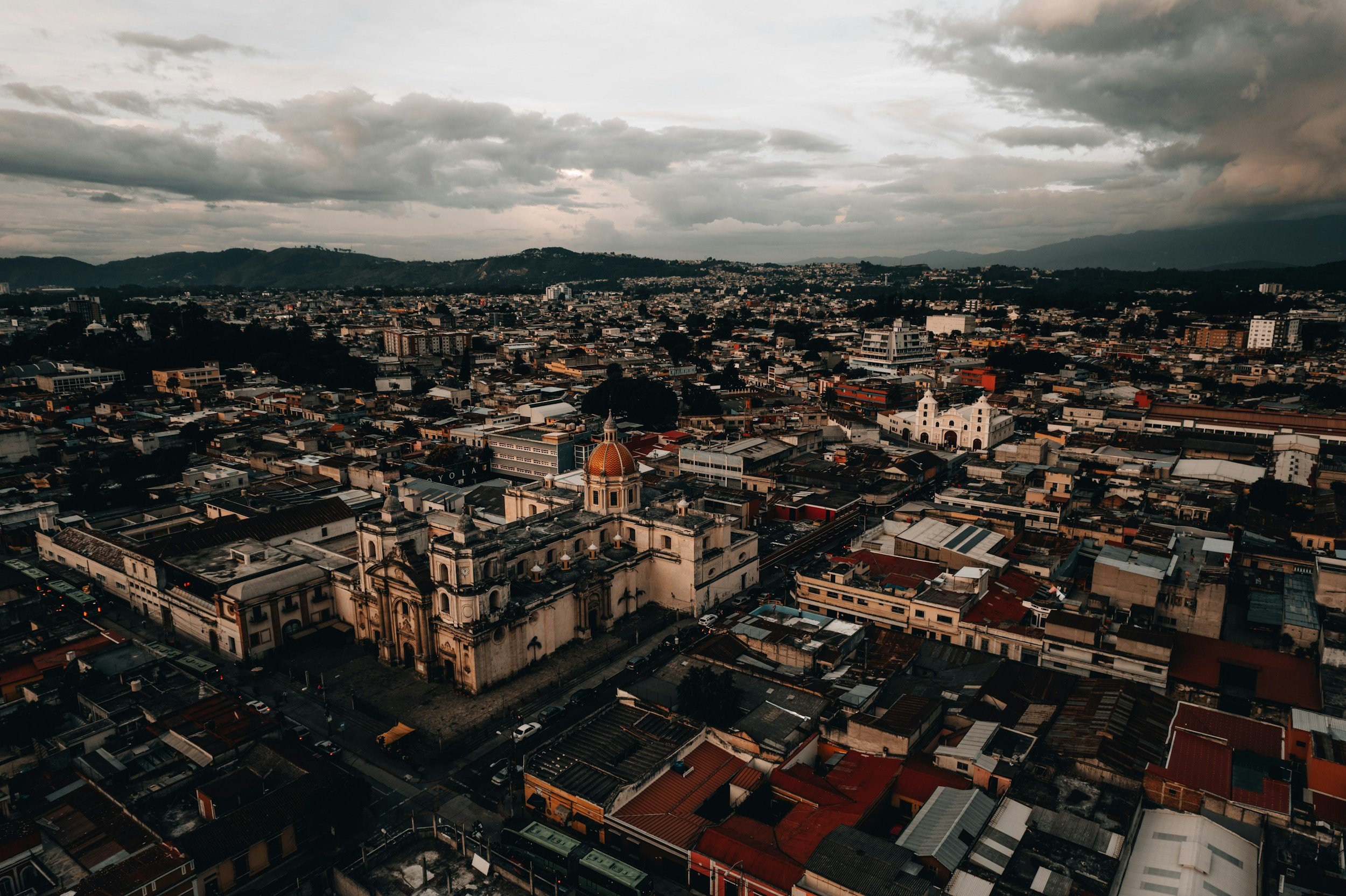 A photograph of Guatemala City with buildings and the mountains in the background on a cloudy day, one of the best places to live in Guatemala City