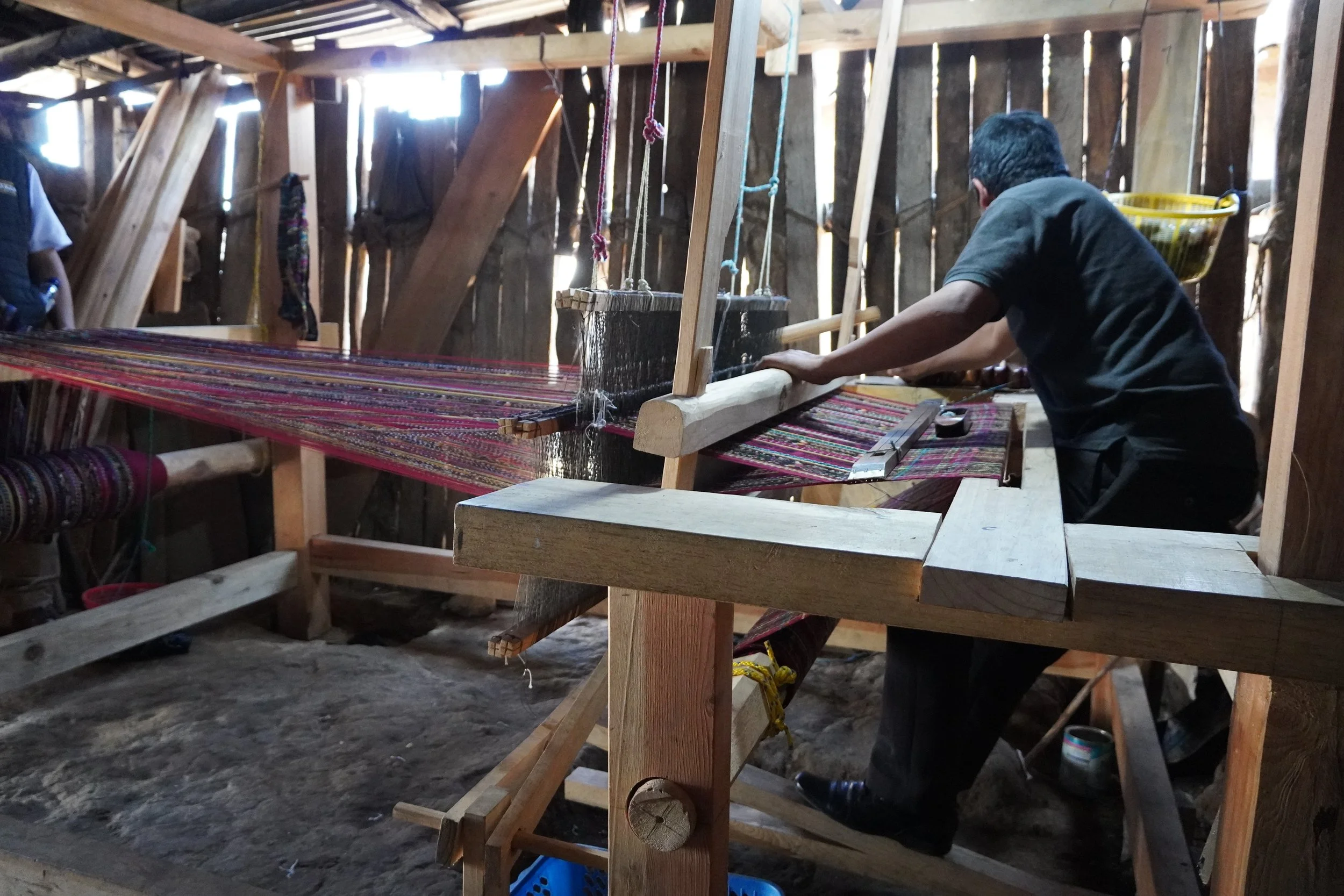 A man is working his loom in his workspace after receiving Microfinance in Latin America.