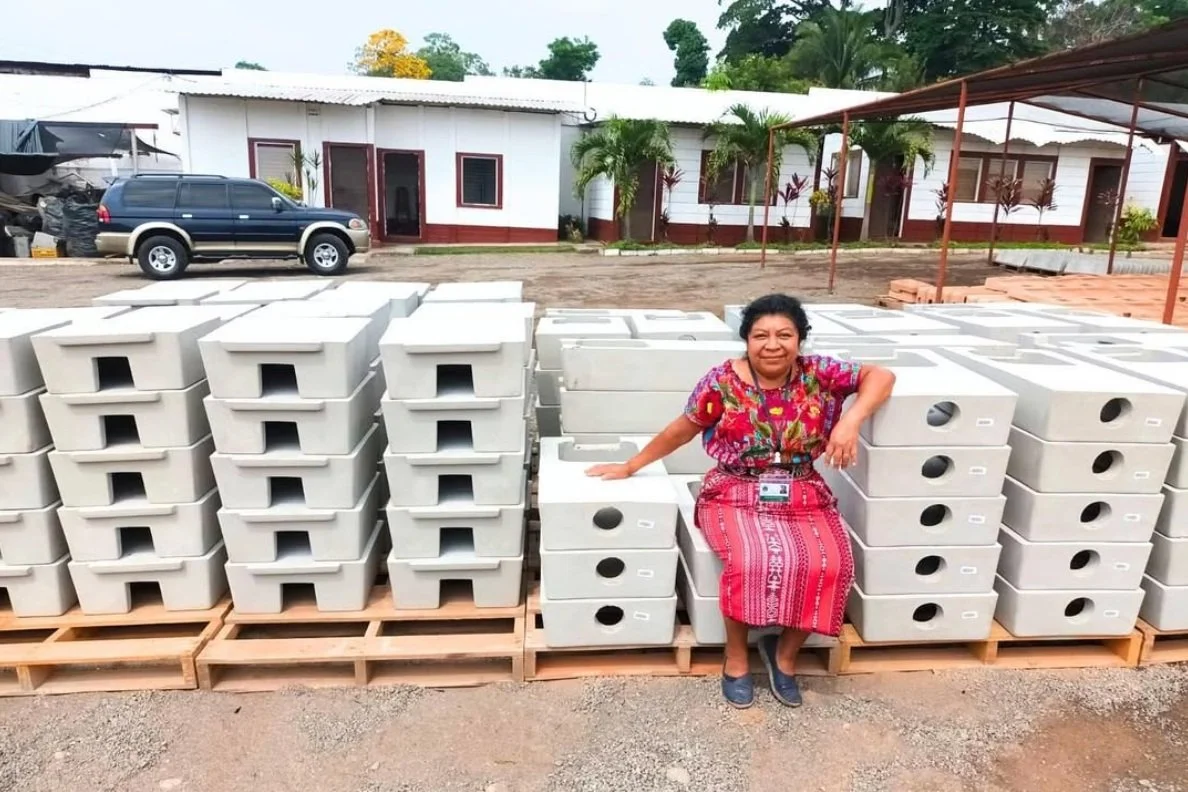 A woman in traditional clothing is sitting on cookstoves from Tui'k Ruch'lew, an organization you can donate to on Giving Tuesday