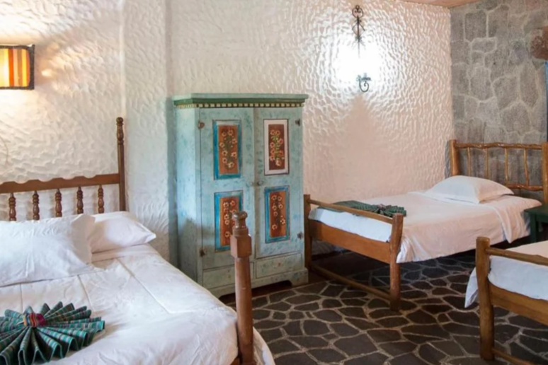 Three beds with white linens are in a Eco Hotel Uxlabil, one of the best eco-friendly Lake Atitlan Hotels