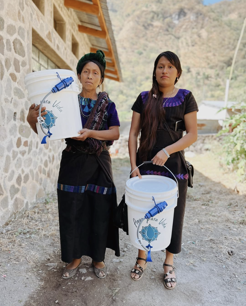 Two Mayan women are holding buckets from Aqua Para Vida, an organization you can donate to on Giving Tuesday