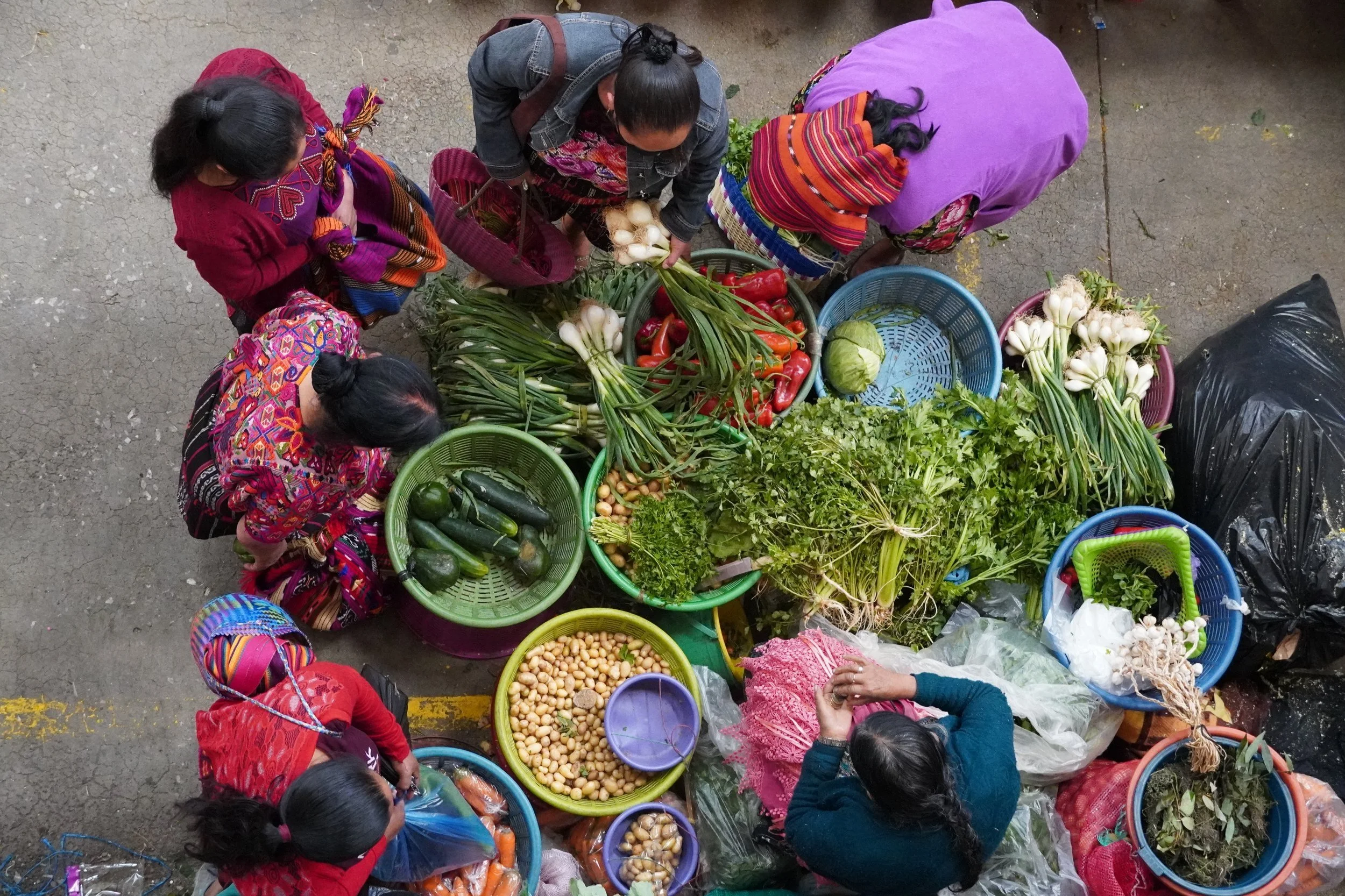 Ladies are shopping vegetables at a farmer's market in Guatemala; the perfect place for finding vegan food in Guatemala