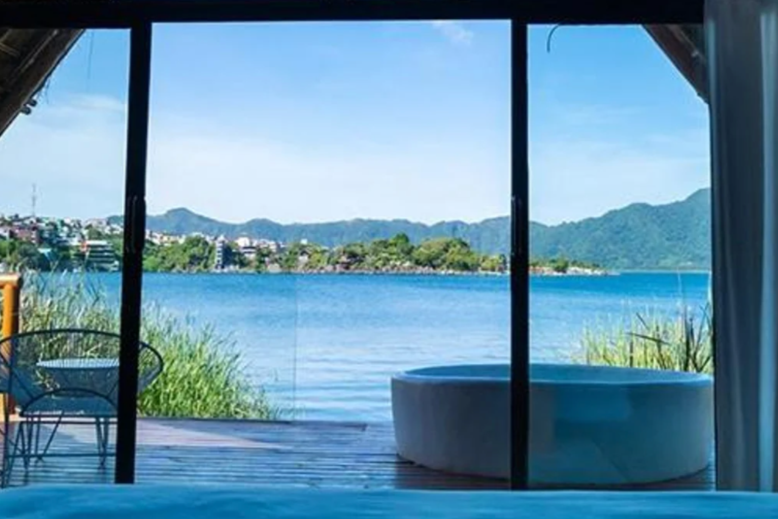 A hot tub and chair on the deck overlooking the water at one of the Lake Atitlan Hotels