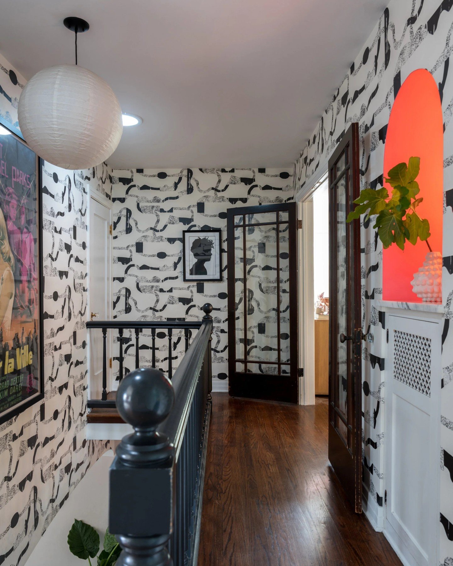 This upstairs hallway was designed to feel like a moment, not just a pass-through. It truly tells the story of the family that lives there. Rich wood floors, graphic wallpaper, and curated art come together to create a layered, soulful pause between 