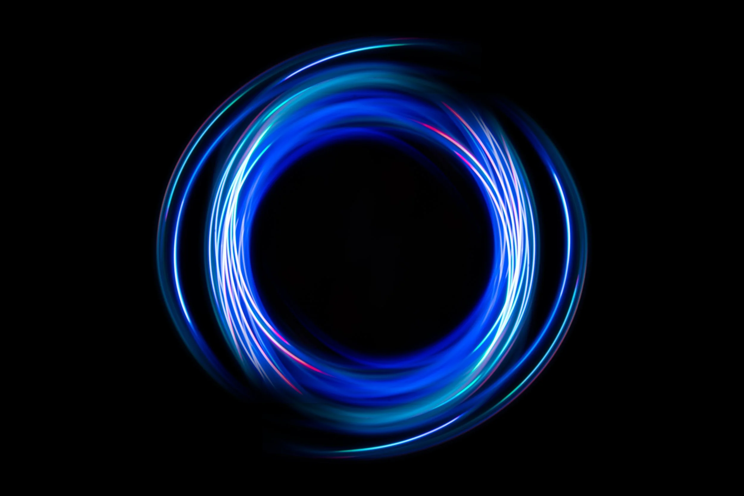 Círculo de luces de neón en tonos azules y morados sobre fondo negro.