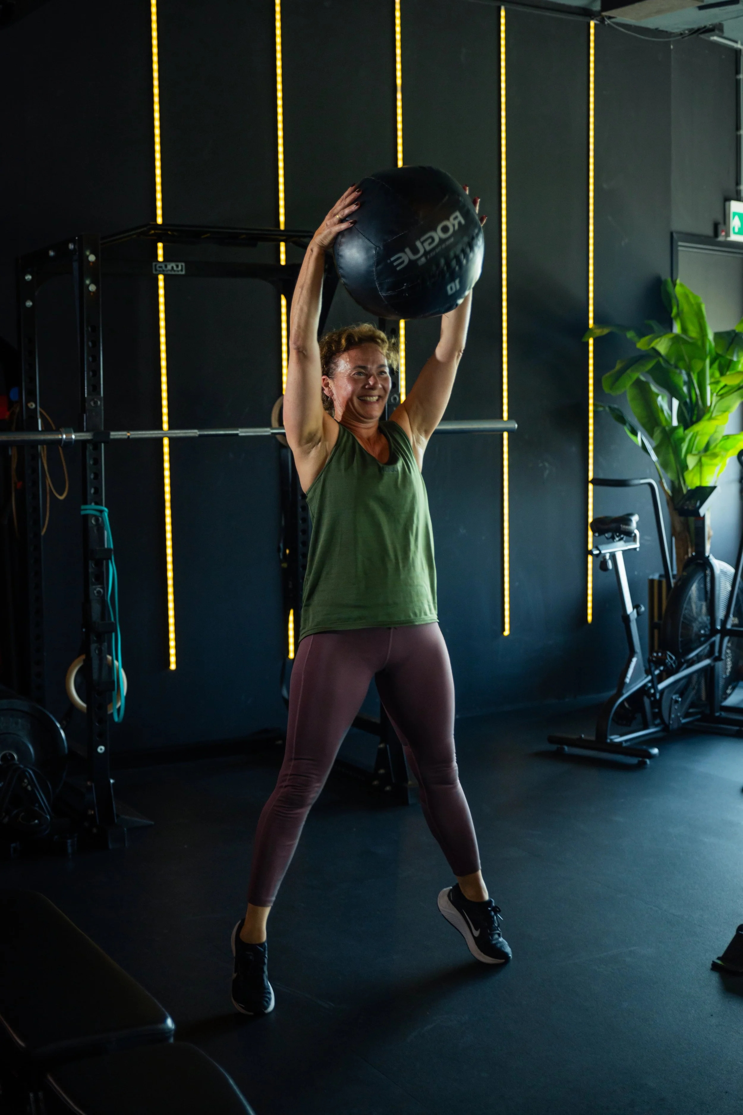 Vrouw voert een medicine ball overhead lift uit tijdens personal training bij The Studio Naarden-Bussum