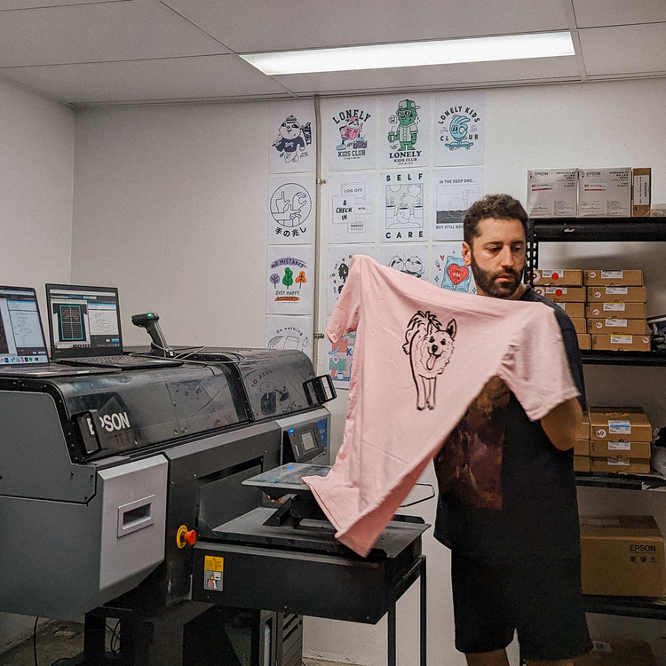 Holding a freshly printed shirt in front of the printers