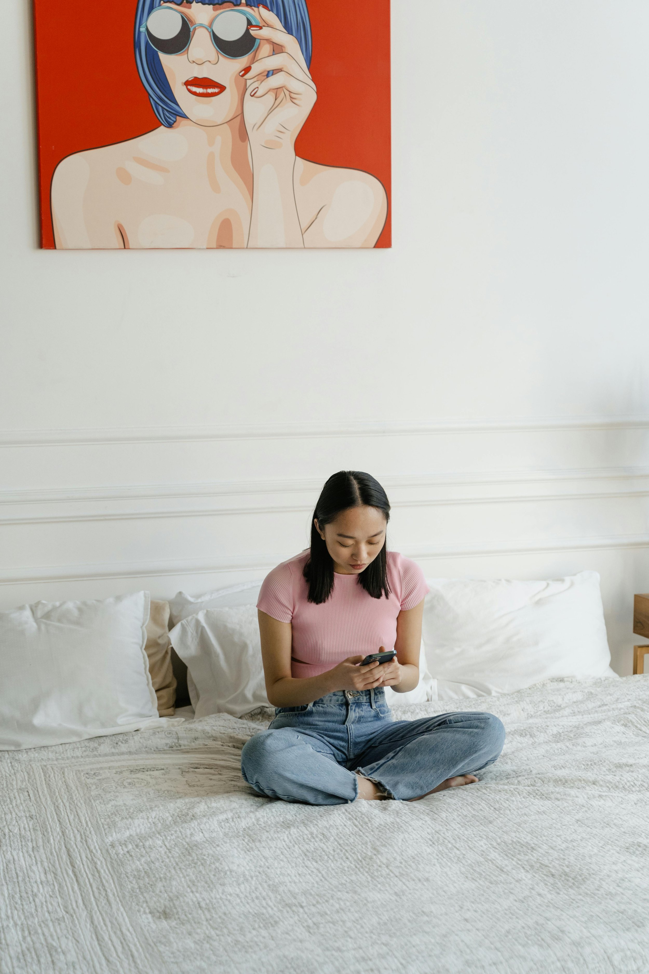Woman sitting on bed looking at phone