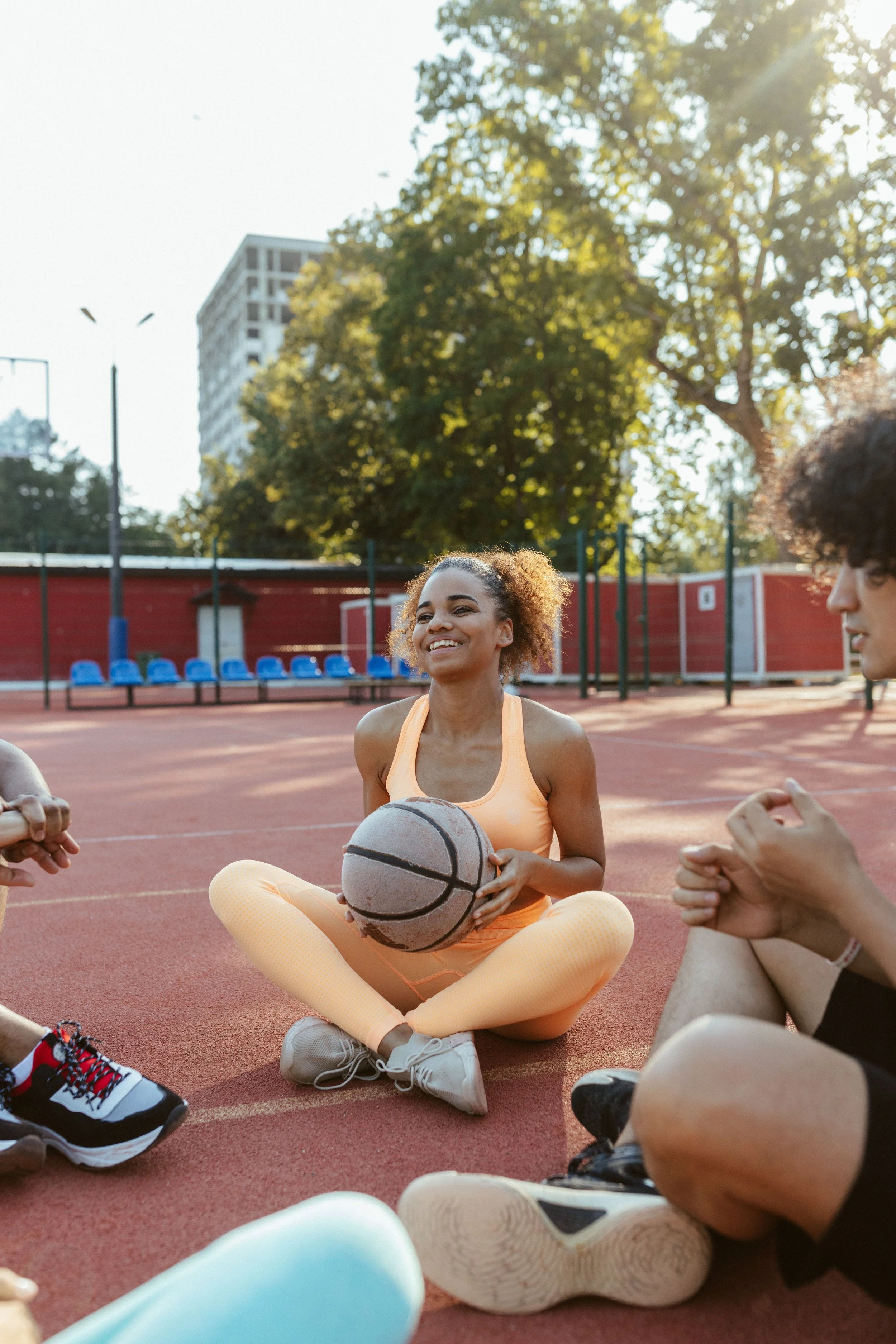 Woman holding a basketball, smiling and sitting with friends